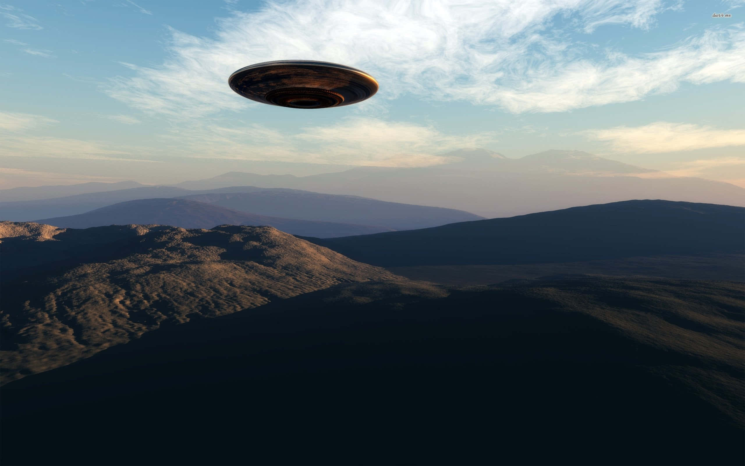 山景 桌布 壁紙 — 一個金屬UFO在柔和的日落天空下，帶著薄雲，盤旋在崎嶇的山脈之上。