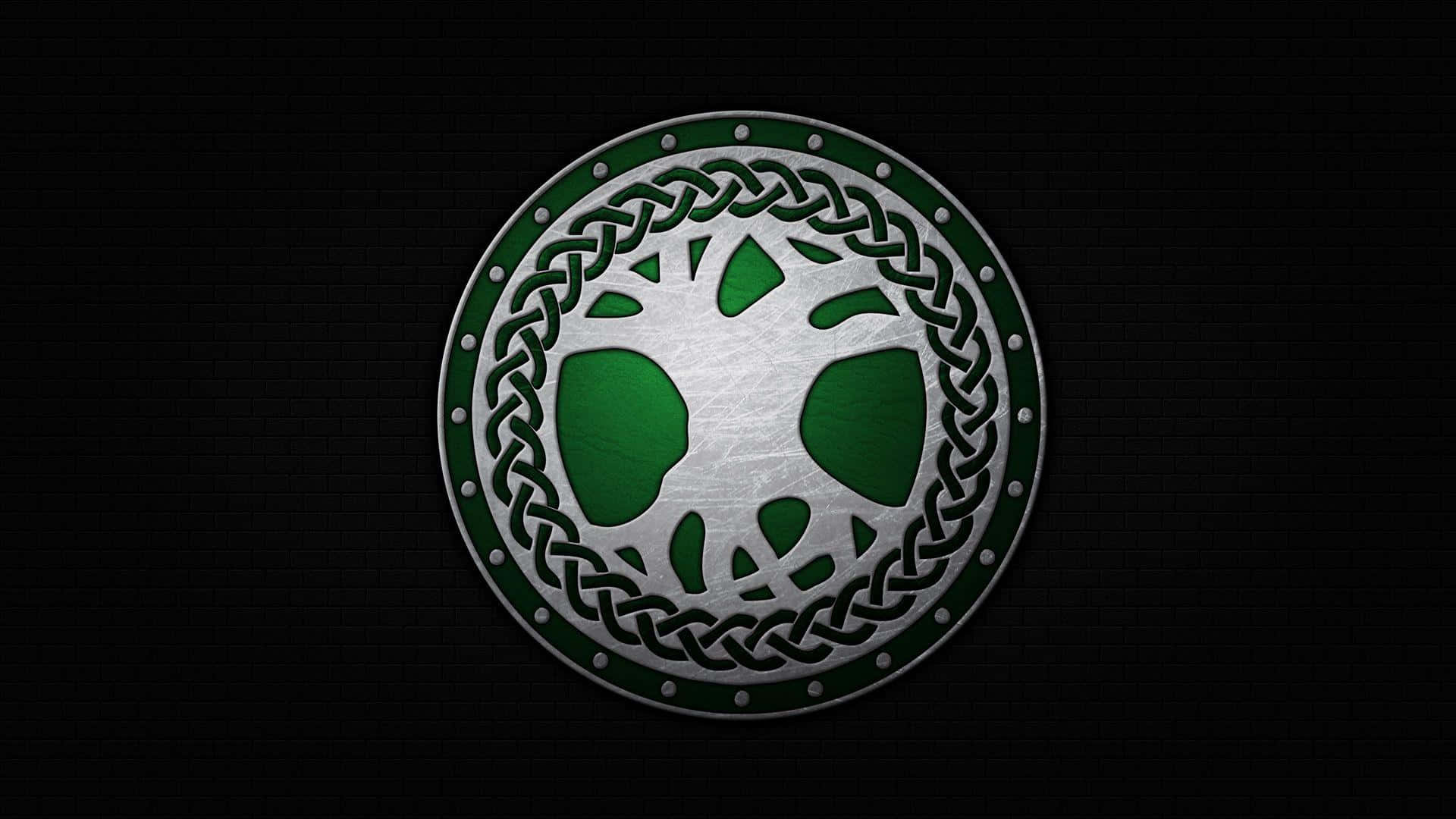 Celtic 桌布 壁紙 — 一個金屬圓形徽章，帶有綠色凱爾特結飾和生命樹鏤空圖案，安裝在黑色磚牆上。