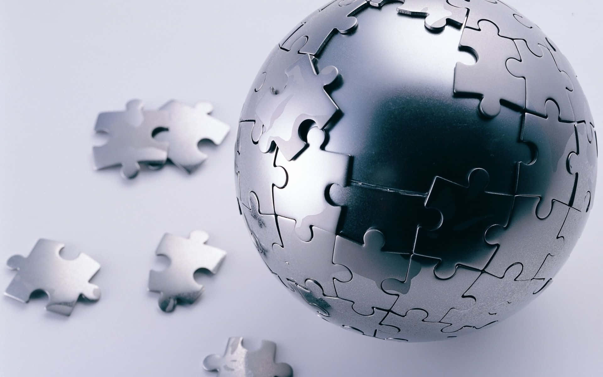 Puzzle 桌布 壁紙 — 一個金屬拼圖地球儀，銀色碎片散落在純白表面上。