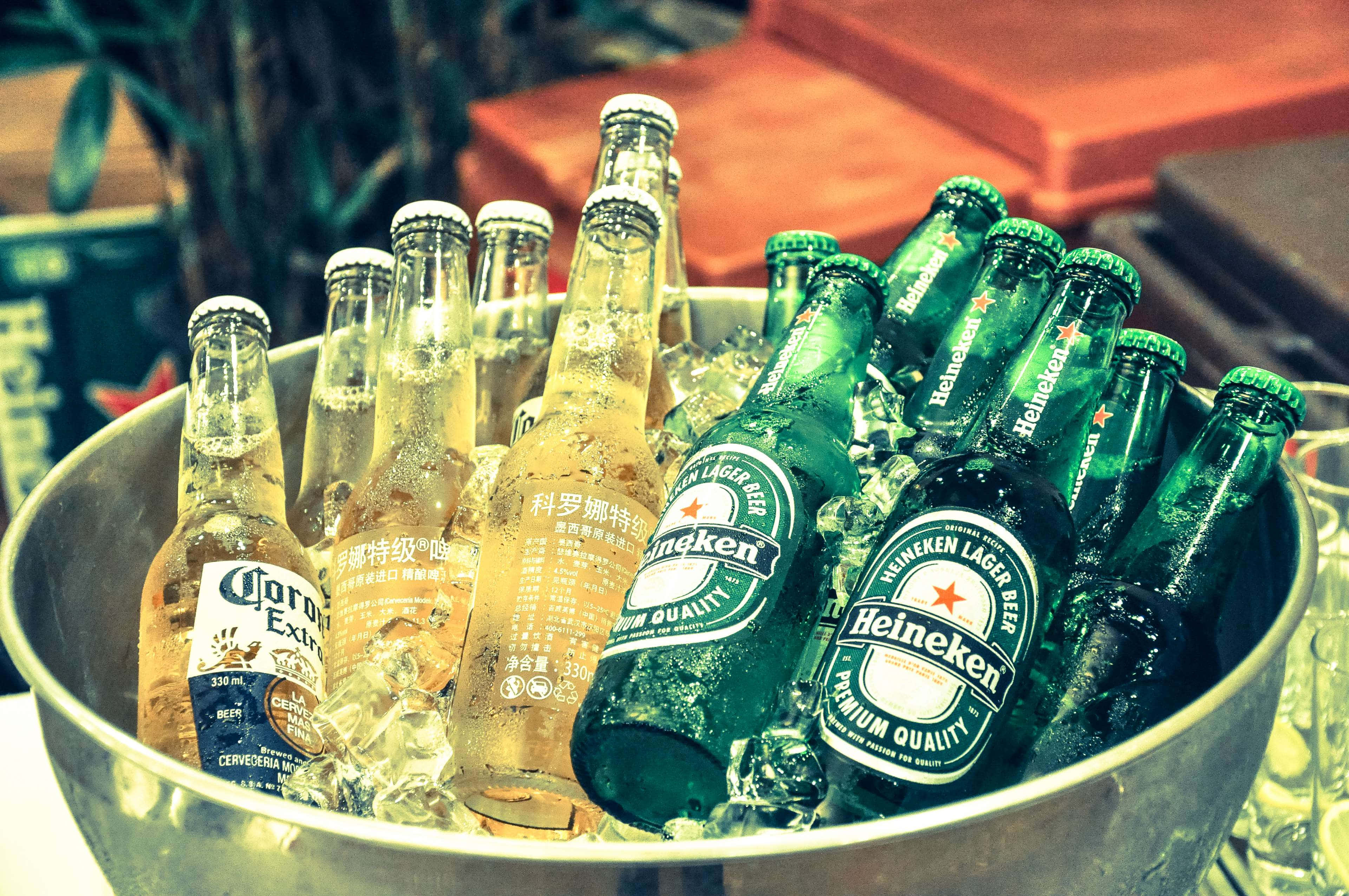 Heineken 桌布 壁紙 — 一個金屬桶裝滿冰塊和各種冰鎮啤酒瓶，包括海尼根和科羅娜特級啤酒。