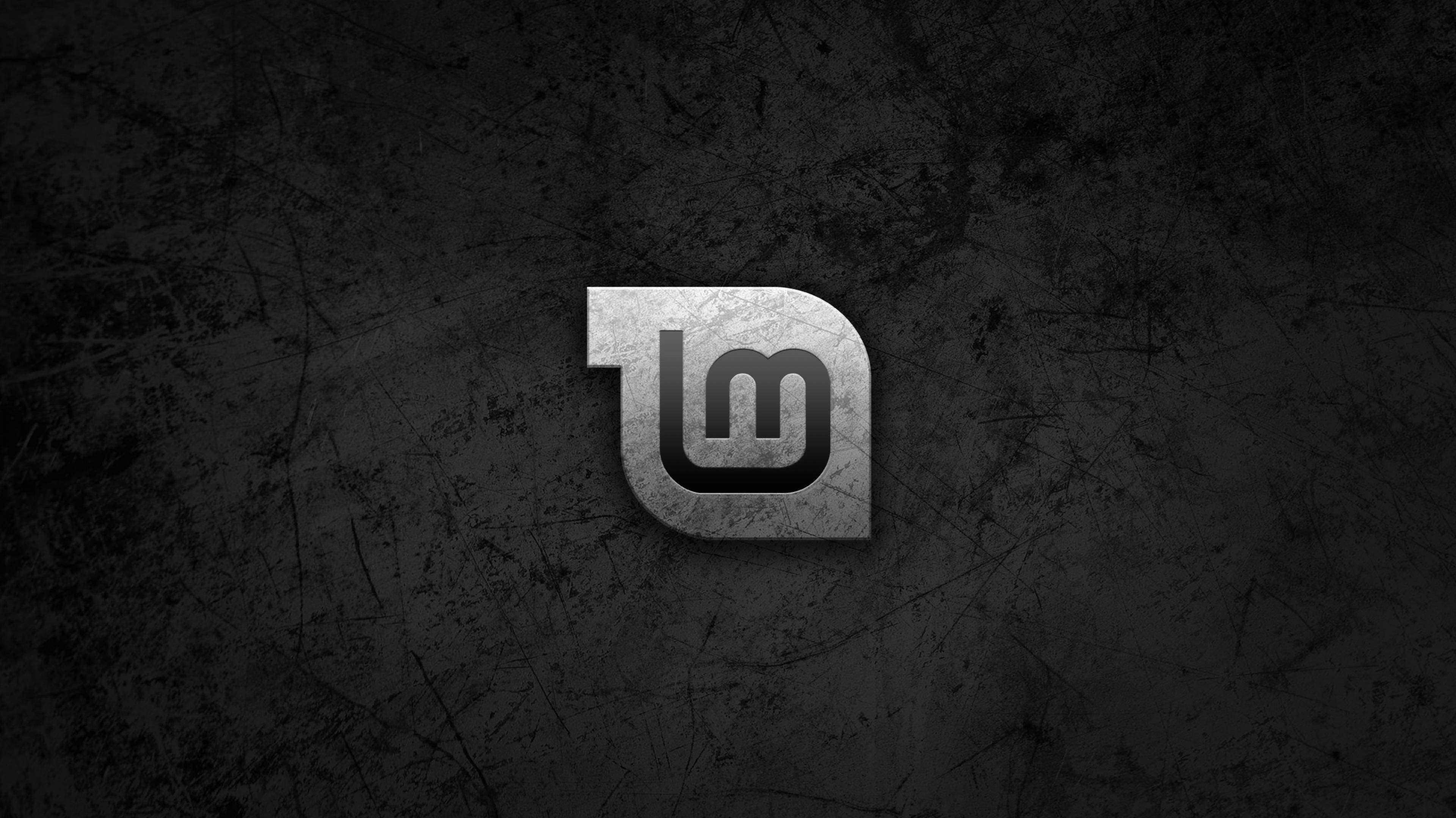 Linux 桌布 壁紙 — 一個金屬標誌，中央有交織的字母「lm」，位於深色刮花牆壁背景上。