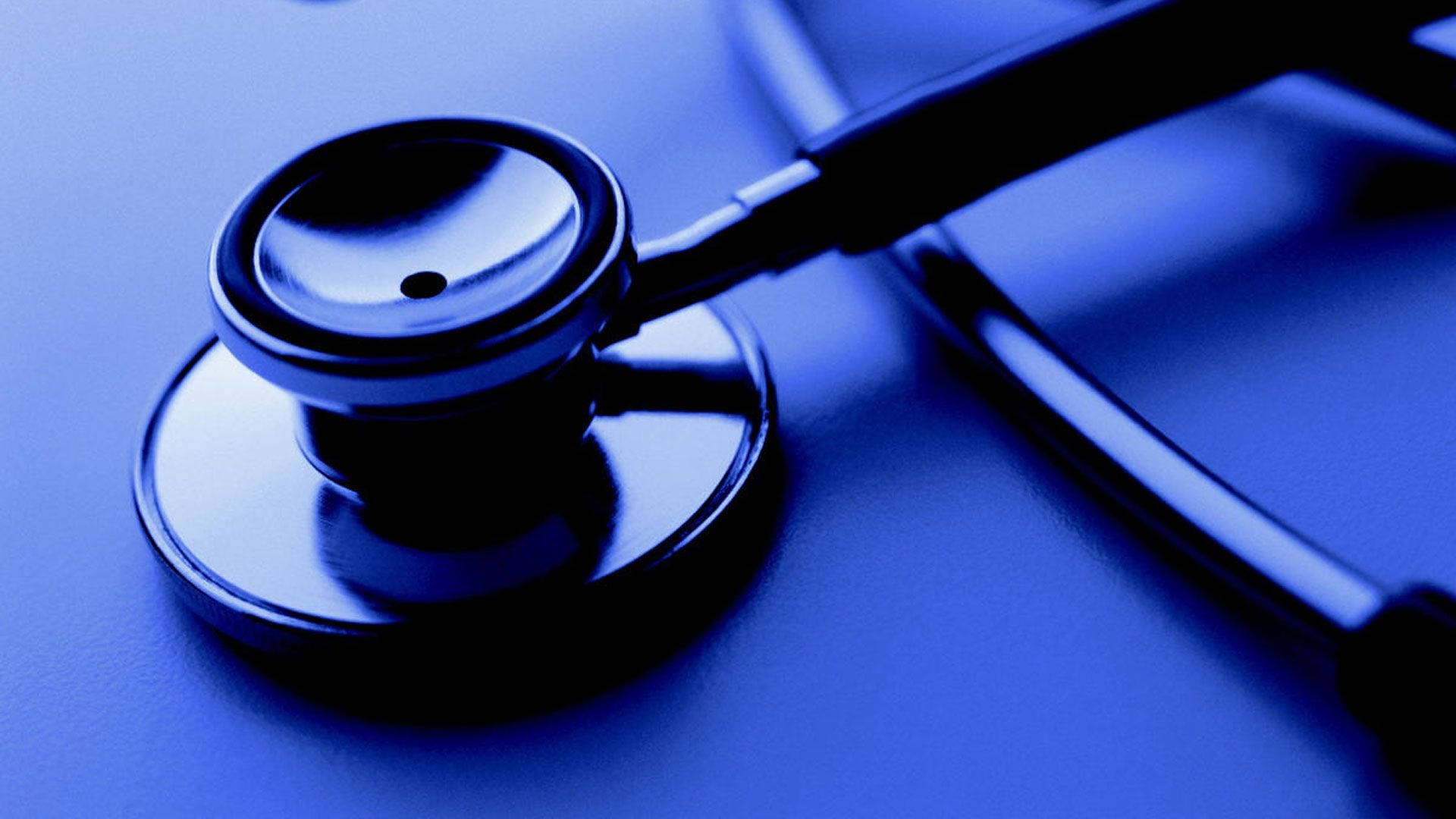 Stethoscope 桌布 壁紙 — 一個金屬胸件聽診器在冷色燈光下放在藍色表面上的特寫。