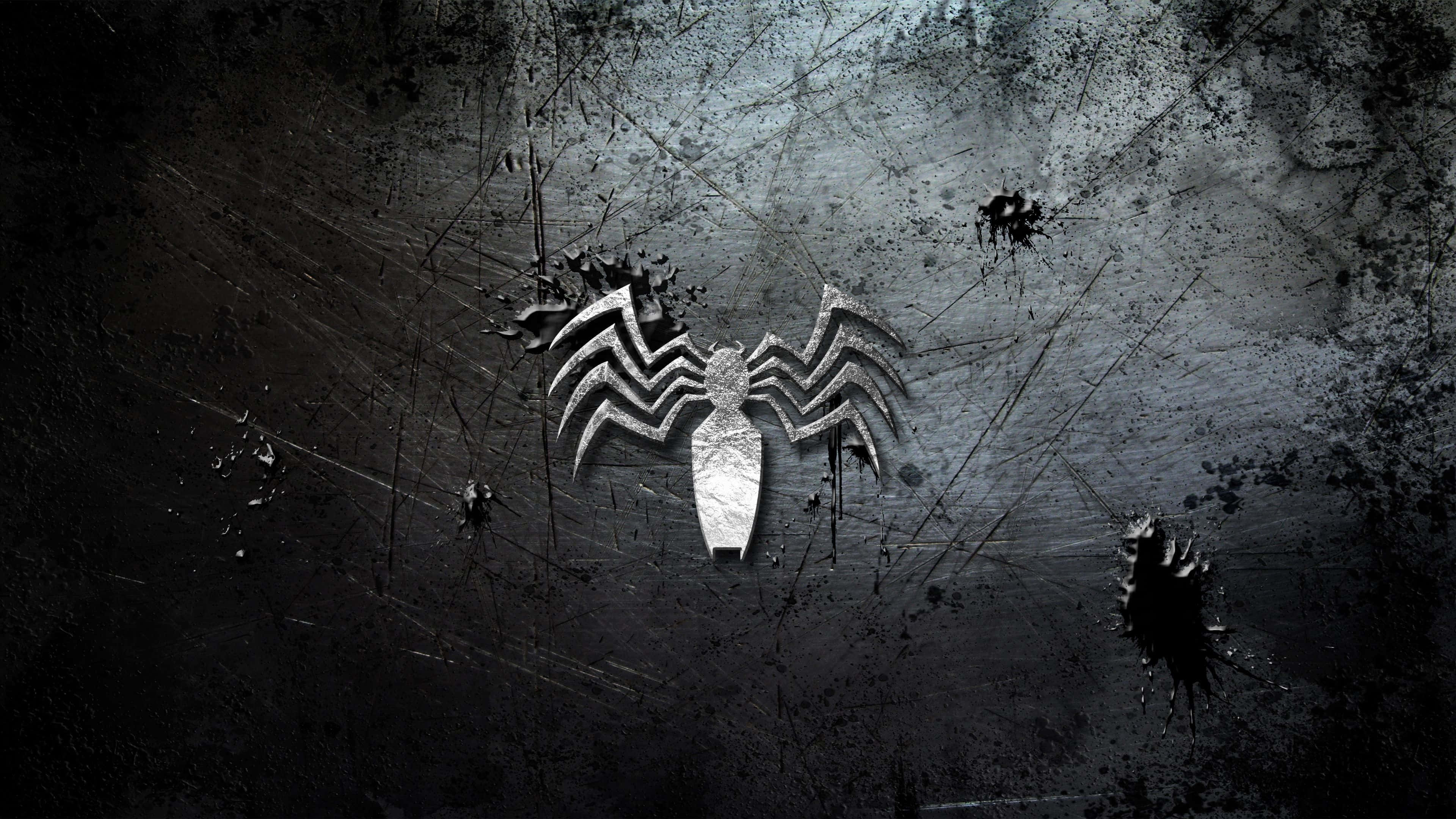 Venom Logo 桌布 壁紙 — 一個金屬蜘蛛標誌在一個粗糙的黑色牆上閃耀，牆上濺滿黑色油漆和刮痕。