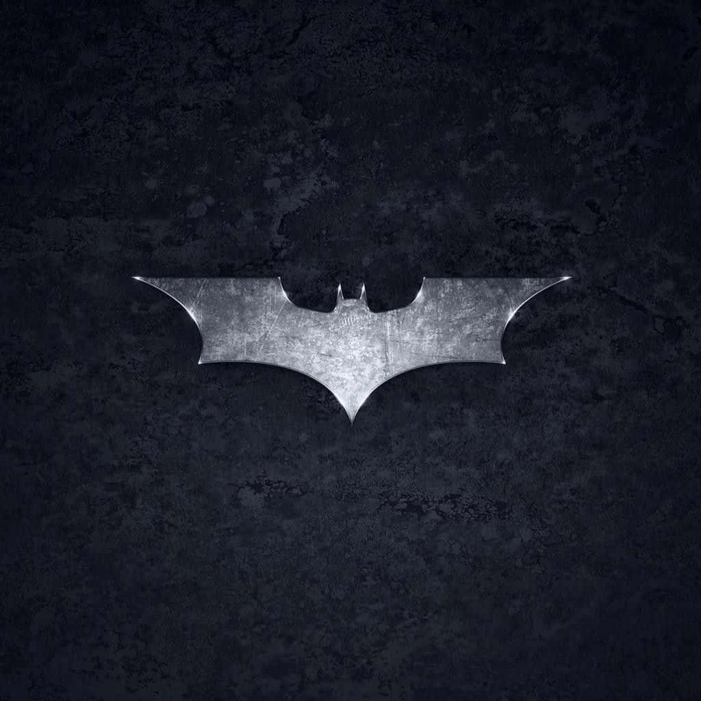 Awesome Batman 桌布 壁紙 — 一個金屬蝙蝠標誌在深色紋理牆壁上閃耀，微妙的燈光突出其邊緣。