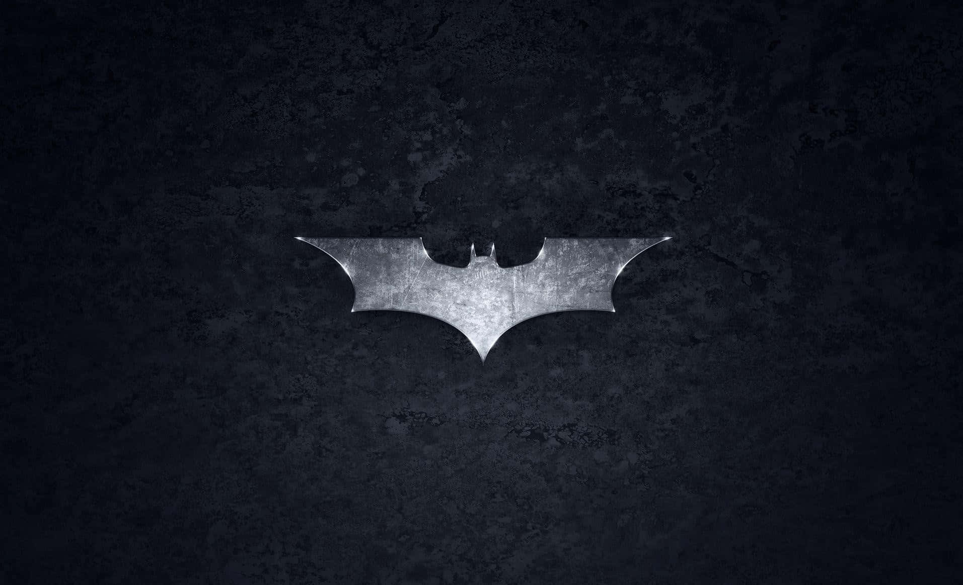 bat 桌布 壁紙 — 一個金屬蝙蝠標誌在黑暗紋理牆壁上閃耀，處於 gritty 的城市環境中。