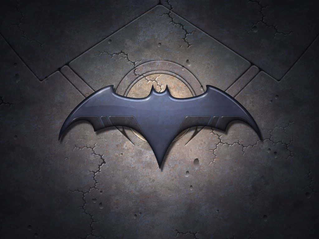 bat 桌布 壁紙 — 一個金屬蝙蝠標誌嵌入在裂開的石磚中，在戲劇性的燈光下。