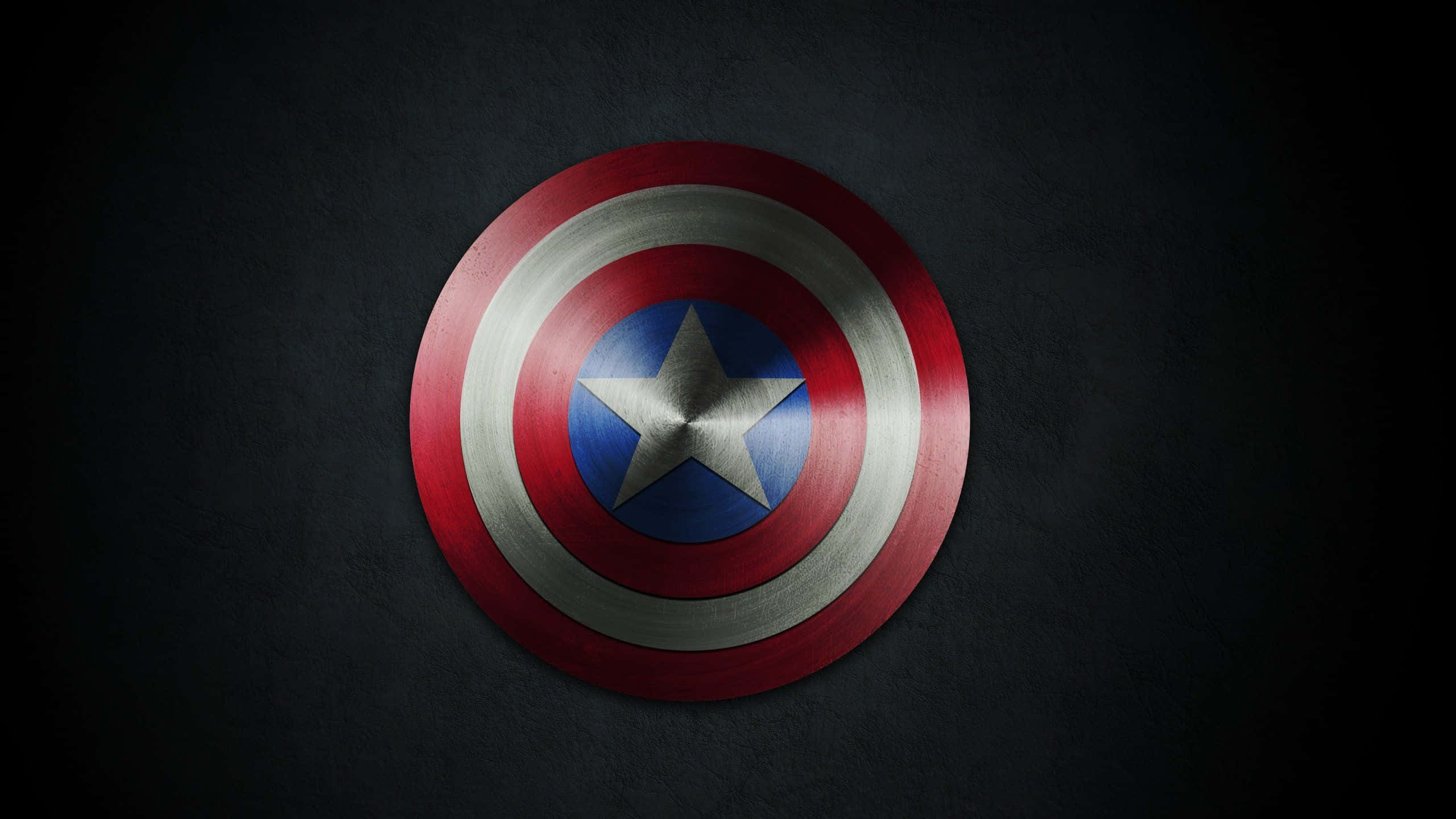 Retro Captain America 桌布 壁紙 — 一個金屬製的美國隊長盾牌，帶有紅、白、藍同心圓和中央的星星，置於深色紋理牆上。