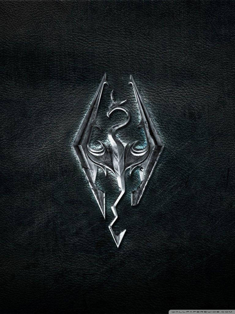 Skyrim Phone 桌布 壁紙 — 一個金屬質感的Skyrim龍紋章蝕刻在深色紋理皮革上，帶有發光的藍色點綴。