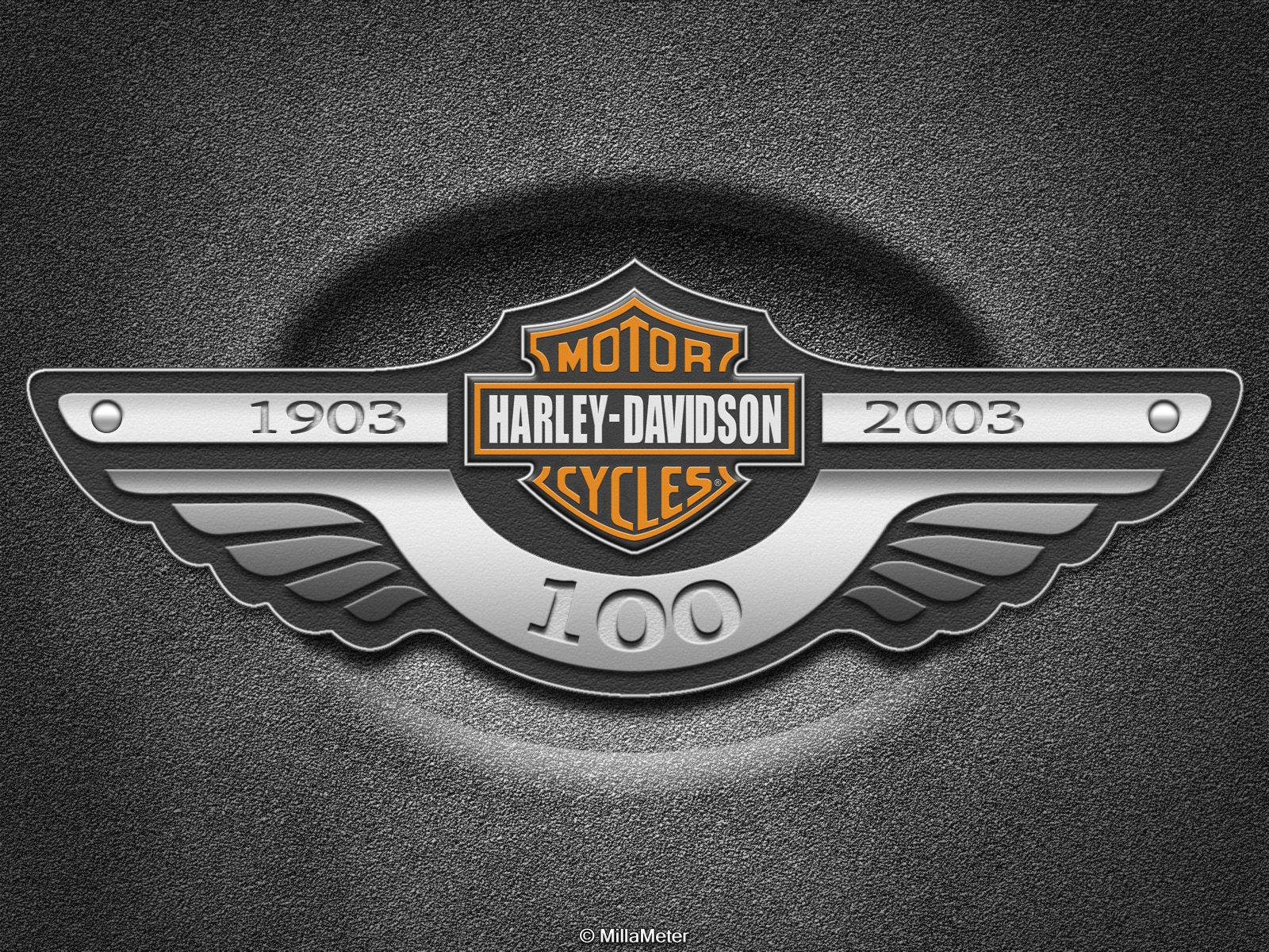 Harley 桌布 壁紙 — 一個金屬質感的哈雷戴維森100週年紀念徽章，帶有翅膀和1903年至2003年的日期，置於紋理深灰色背景上。