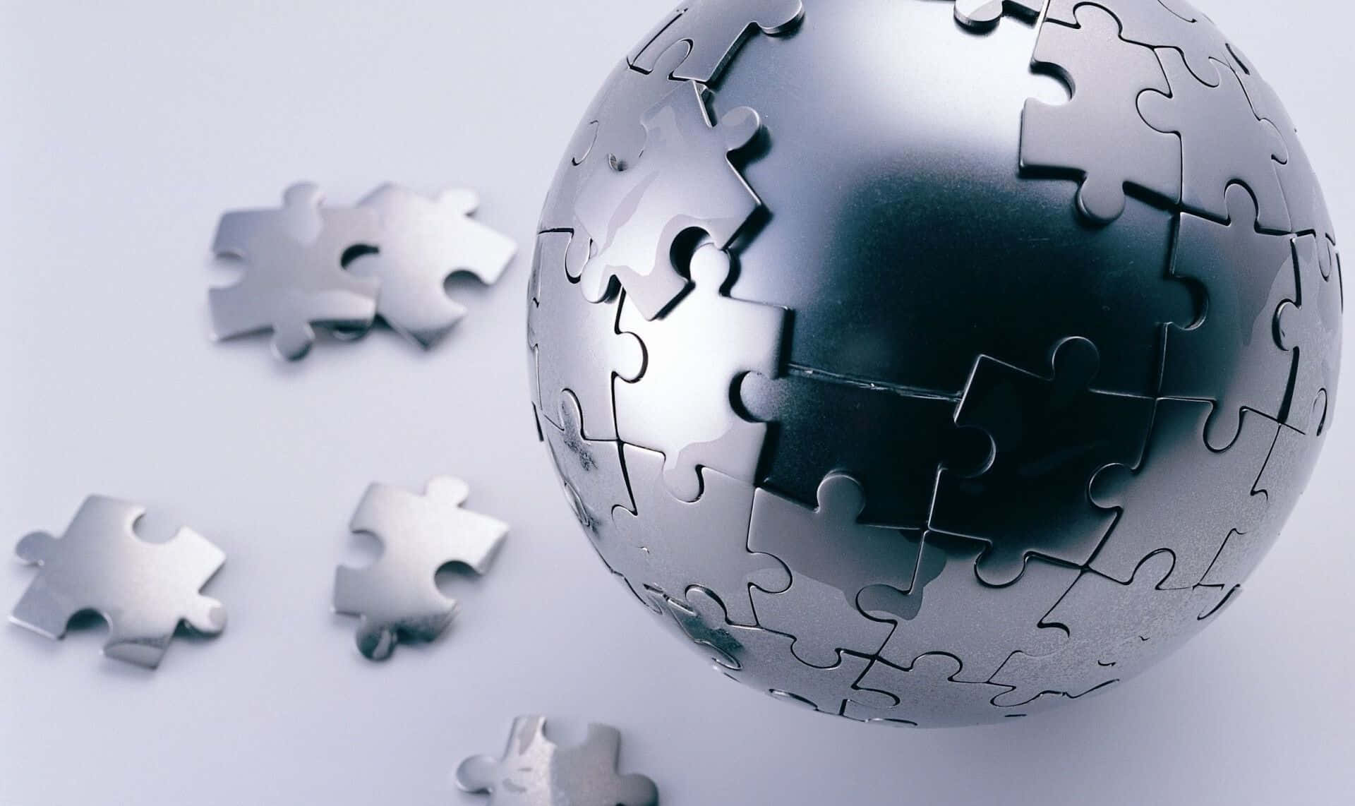 Puzzle Games 桌布 壁紙 — 一個金屬銀色拼圖地球儀，淺灰色表面上散落著拼圖塊。