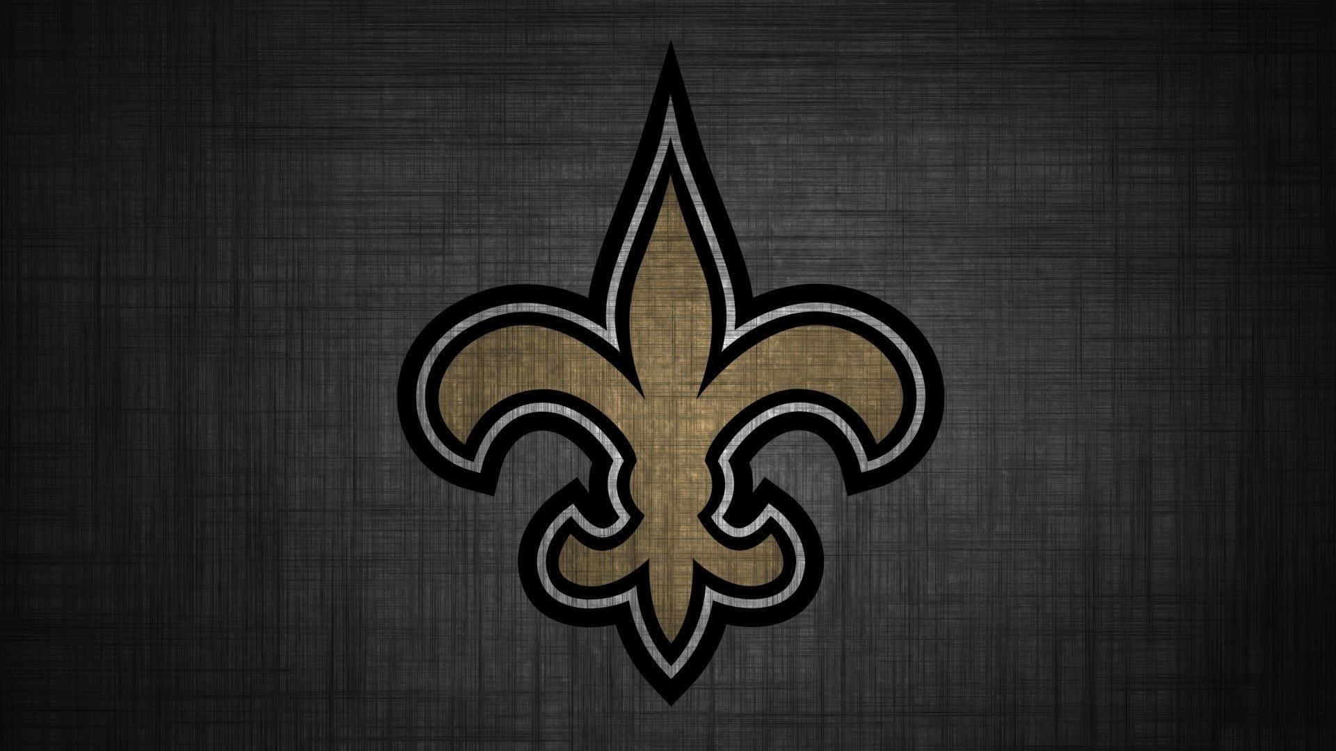 NFL Saints 桌布 壁紙 — 一個金色和黑色的百合花飾標誌，居中放置在帶有紋理的深灰色布料背景上。