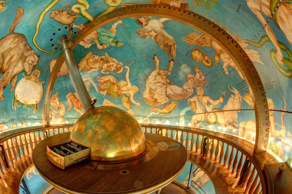 Planetarium 桌布 壁紙 — 一個金色天球儀放在木製底座上，下方是一個繪有黃道十二宮星座和神話人物的圓頂。