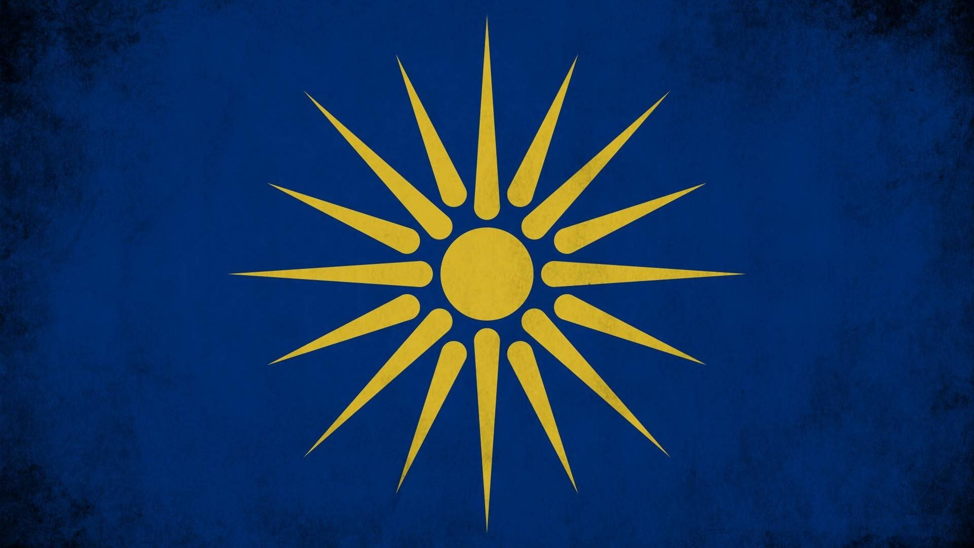 Macedonia 桌布 壁紙 — 一個金色太陽光線徽章從帶紋理的深藍色背景中心向外放射。