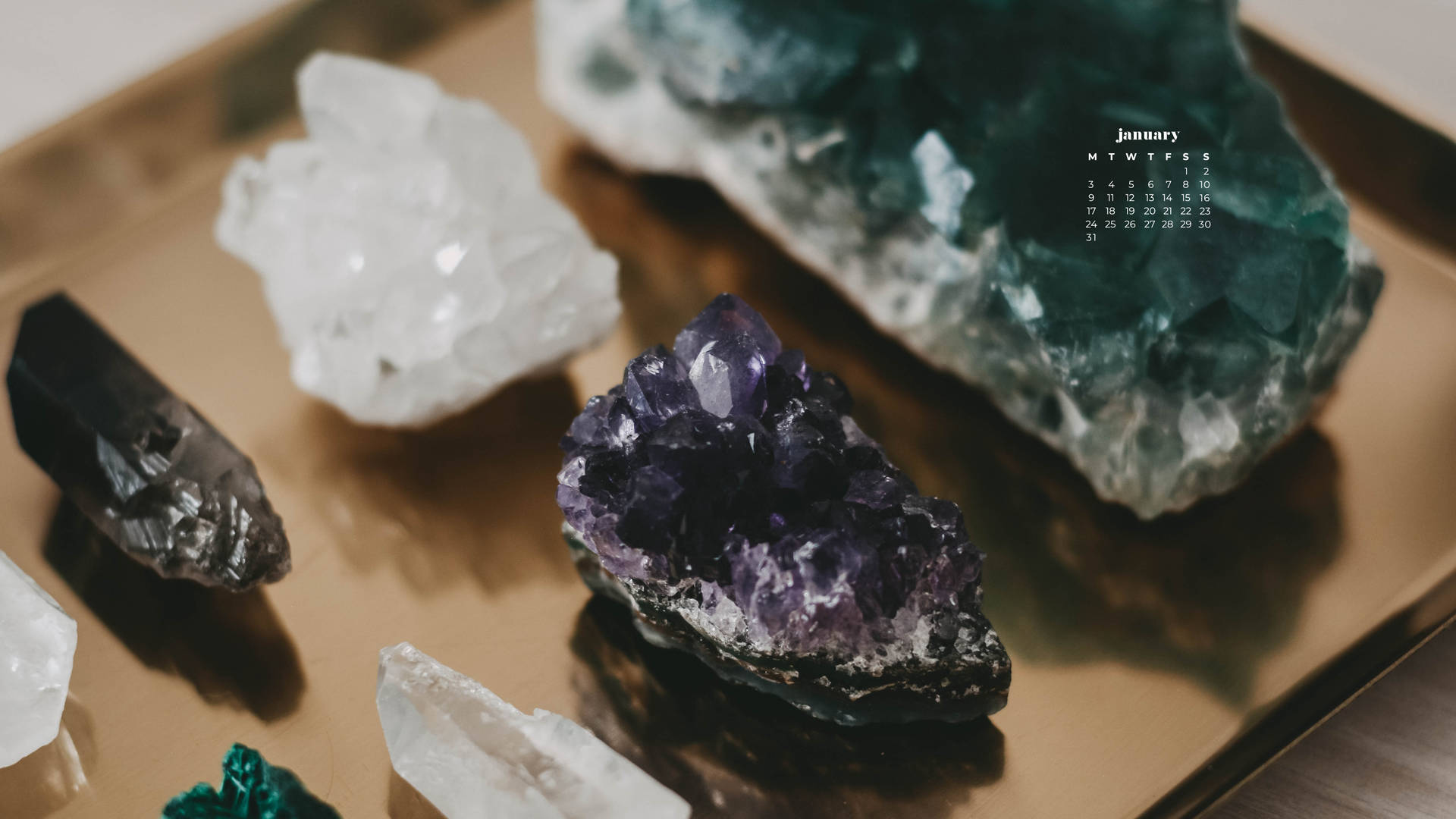 金色托盤上色彩繽紛的水晶收藏，附有一月日曆覆蓋層。 — 一月 GIF 壁紙