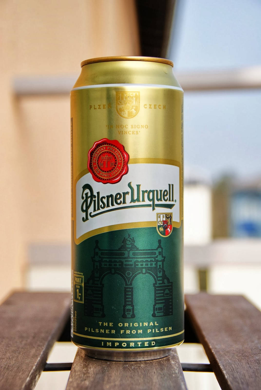 Brewers 桌布 壁紙 — 一個金色的Pilsner Urquell啤酒罐在明亮的日光下直立於戶外的木桌上。