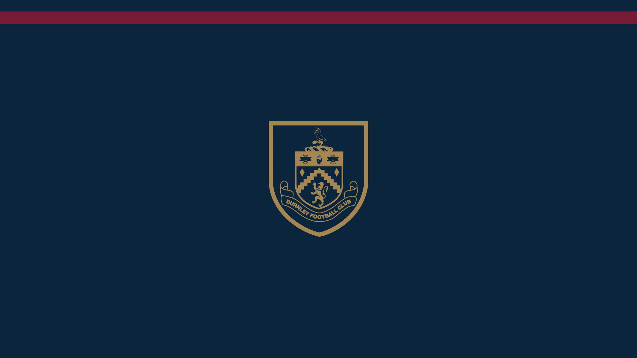 Burnley Fc 桌布 壁紙 — 一個金色的伯恩利足球俱樂部徽章置於深藍色背景中央，頂部有一條栗色條紋。