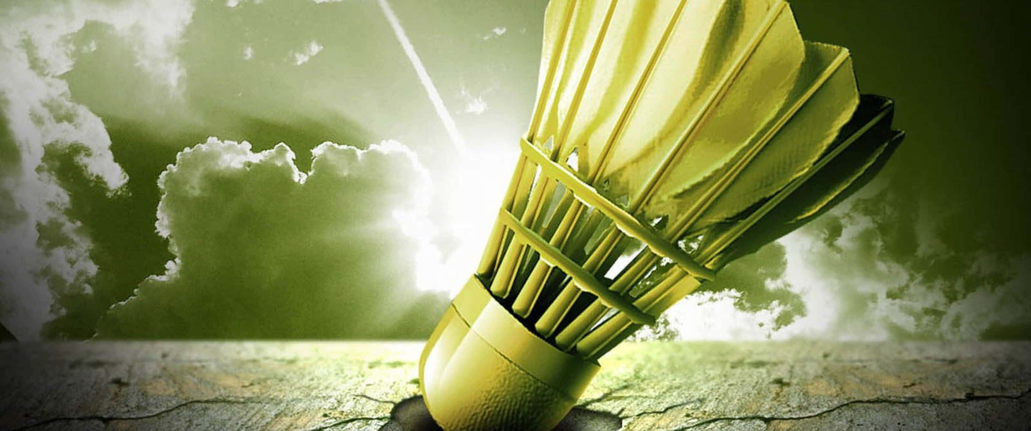 3440x1440p Badminton 桌布 壁紙 — 一個金色羽毛球在裂開的地上，背景是戲劇性的綠色天空和明亮的陽光。