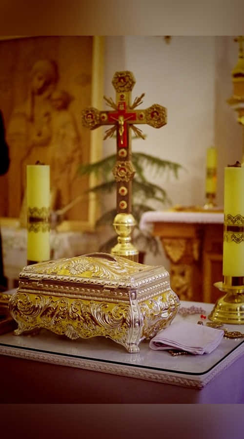 Sacrament 桌布 壁紙 — 一個金色華麗的聖物箱放在祭壇上，旁邊有十字架和黃色蠟燭，教堂內部燈光溫暖。