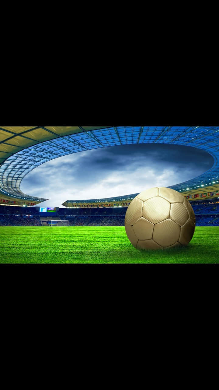 Android Football 桌布 壁紙 — 一個金色足球放在一個巨大體育館的鮮綠色草地上，上方是戲劇性的多雲天空。