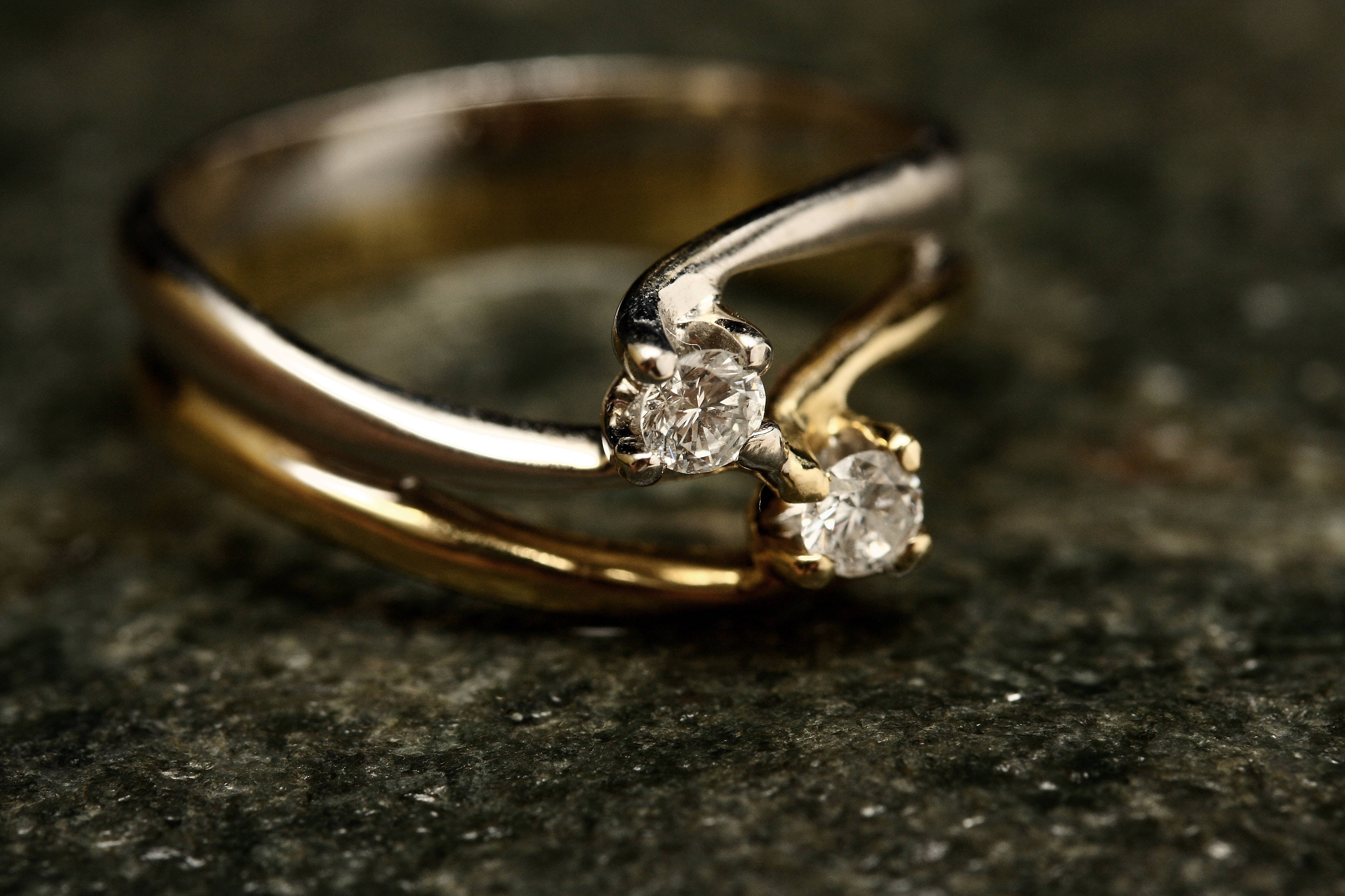 Gold Jewellery 桌布 壁紙 — 一個金銀鑽石戒指的特寫，戒指上有兩顆寶石，放置在深色紋理石面上。