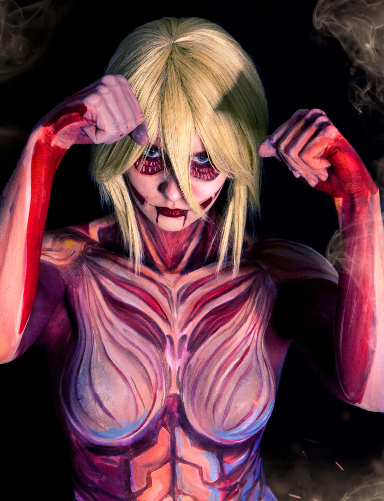 Female Titan 桌布 壁紙 — 一個金髮和紅色肌肉塗料的人，在黑暗煙霧背景中展示肌肉。