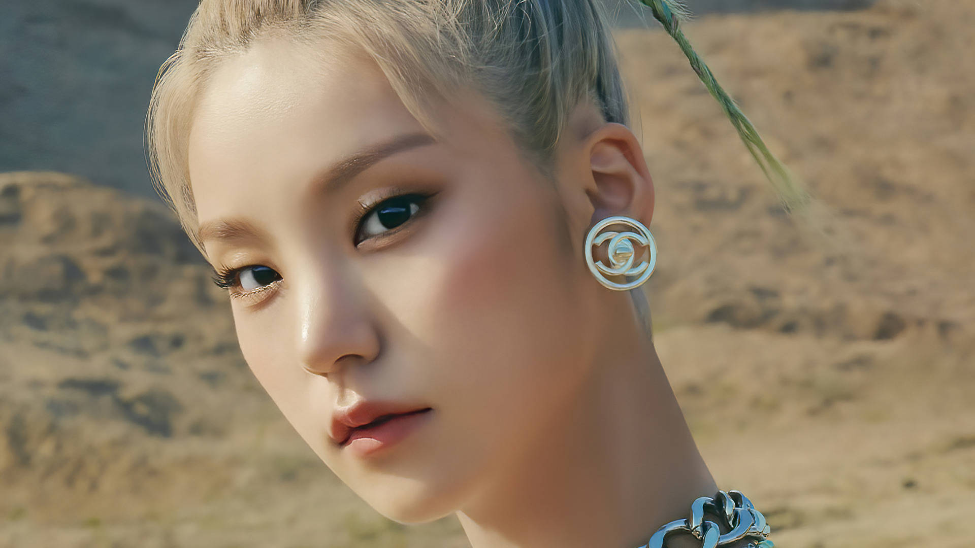 ITZY 桌布 壁紙 — 一個金髮女子的特寫肖像，化了濃妝，背景是陽光普照的沙漠。