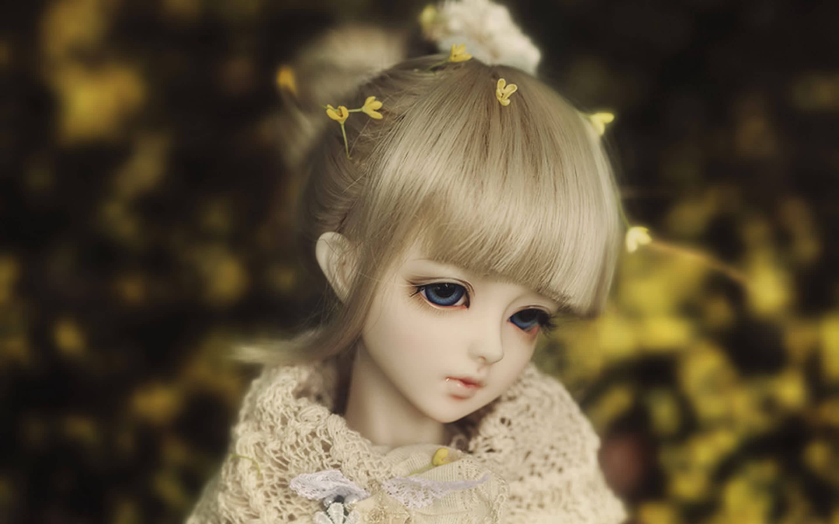 Doll 桌布 壁紙 — 一個金髮娃娃的特寫，頭上裝飾著黃色花朵，穿著蕾絲領，背景是金色模糊效果。