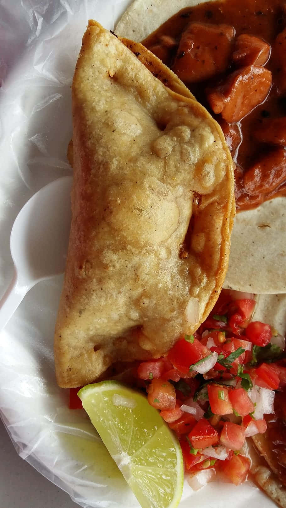 Mexican 桌布 壁紙 — 一個金黃色的炸餡餅放在白色盤子上，旁邊有粗粒紅莎莎醬和萊姆角。