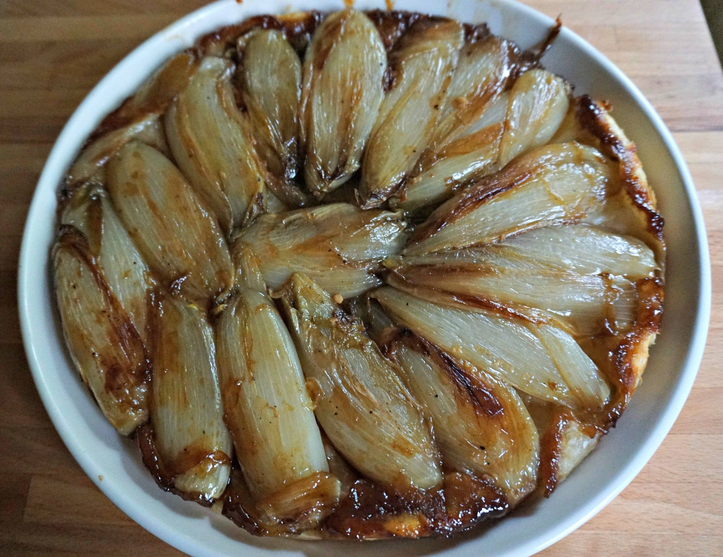 Pie 桌布 壁紙 — 一個金黃色的焦糖洋蔥塔，在木質表面上以白色陶瓷盤完美地排列成螺旋形。