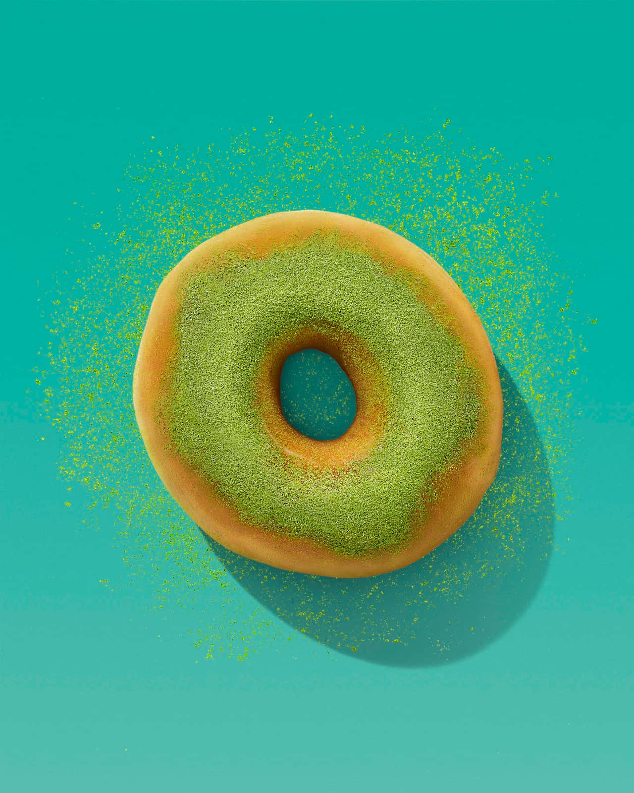 Donut 桌布 壁紙 — 一個金黃色的甜甜圈，撒上鮮綠色粉末，置於純青色背景中央，周圍散落著碎屑。