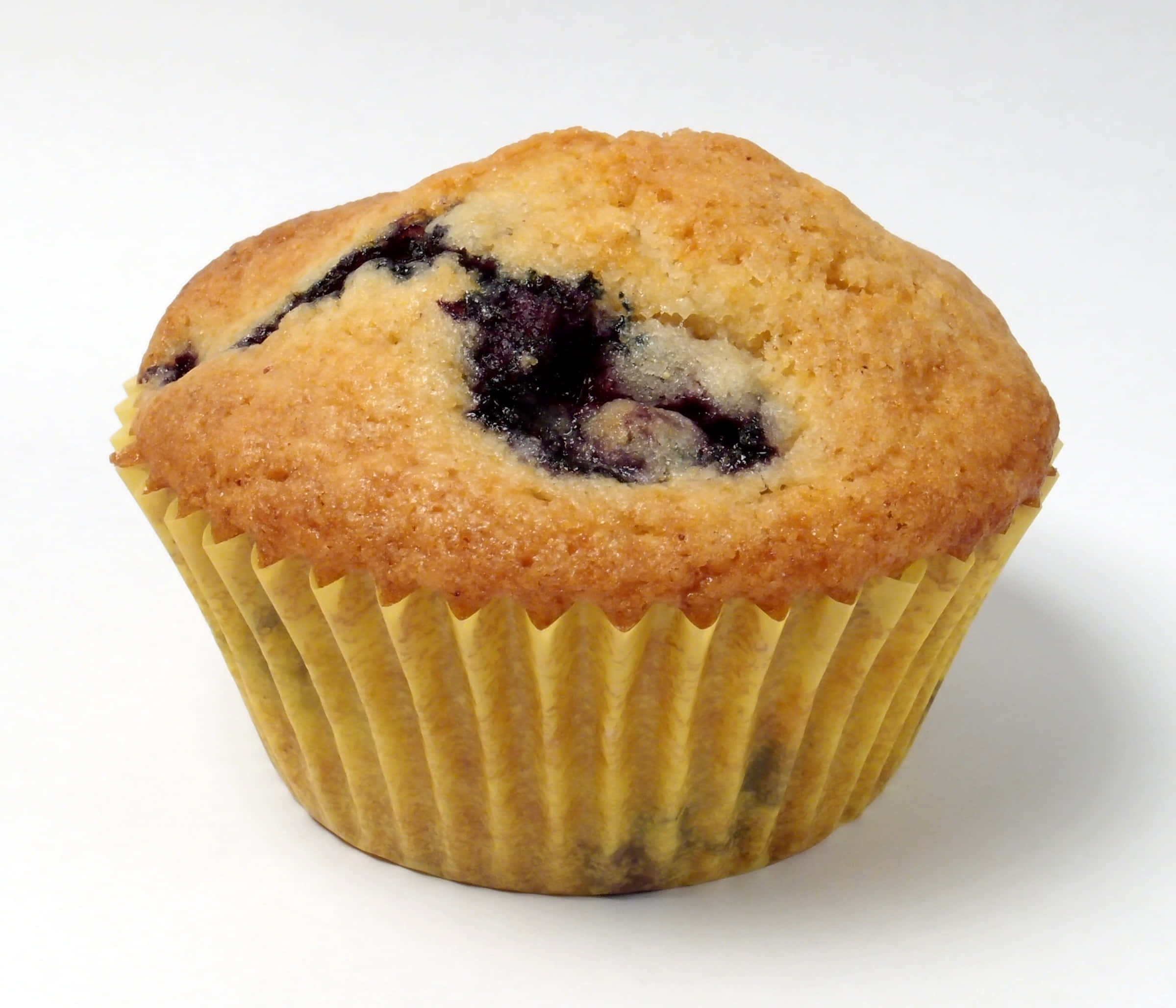 Blueberry Muffins 桌布 壁紙 — 一個金黃色的藍莓馬芬，頂部爆出多汁的深色莓果，放在黃色波浪紋紙杯裡，襯著潔白的背景。