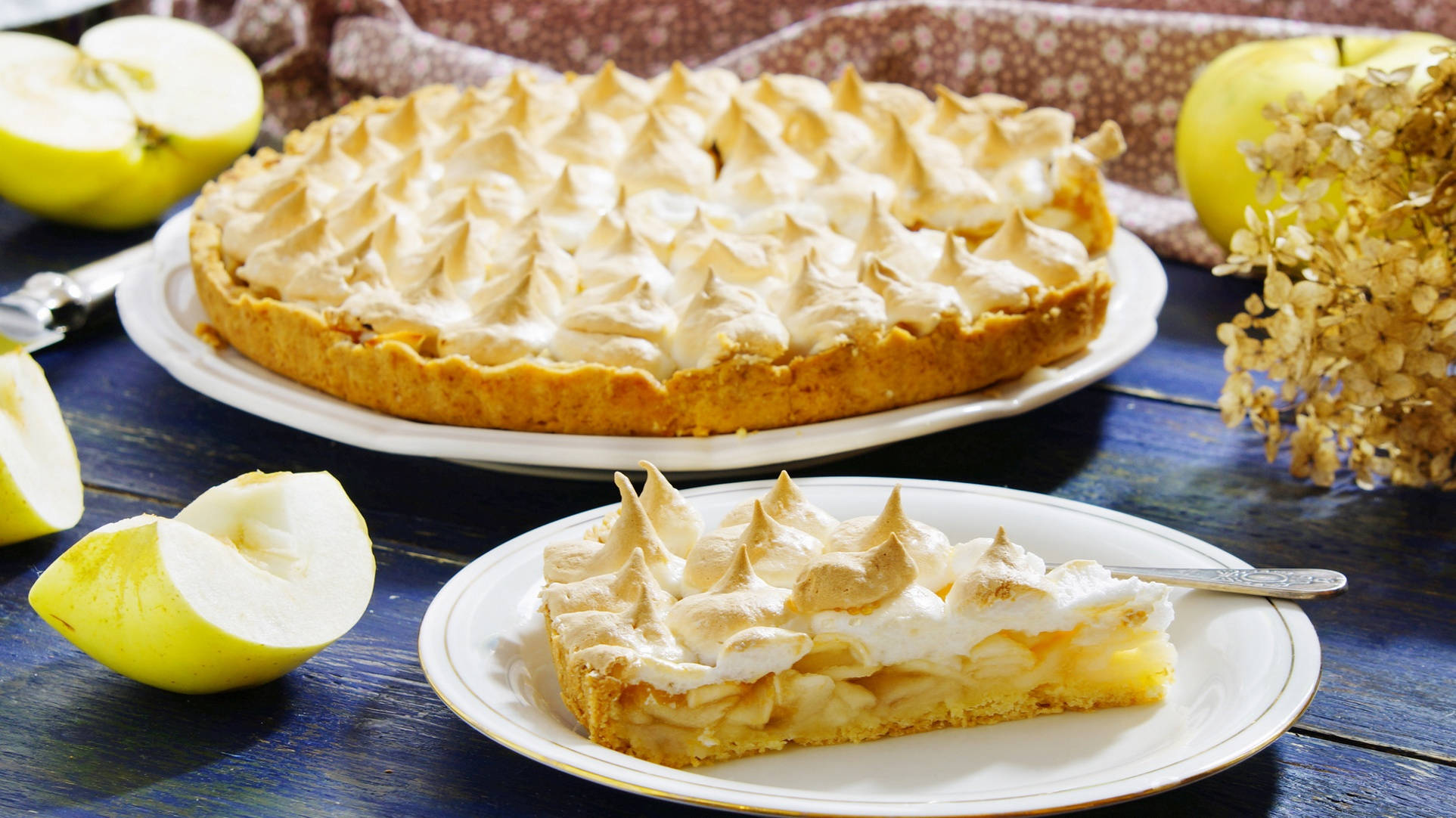 Pie 桌布 壁紙 — 一個金黃色的蘋果派，上面鋪滿蓬鬆的蛋白霜，放在一張質樸的藍色木桌上，旁邊有新鮮蘋果和盤子上的一片派。