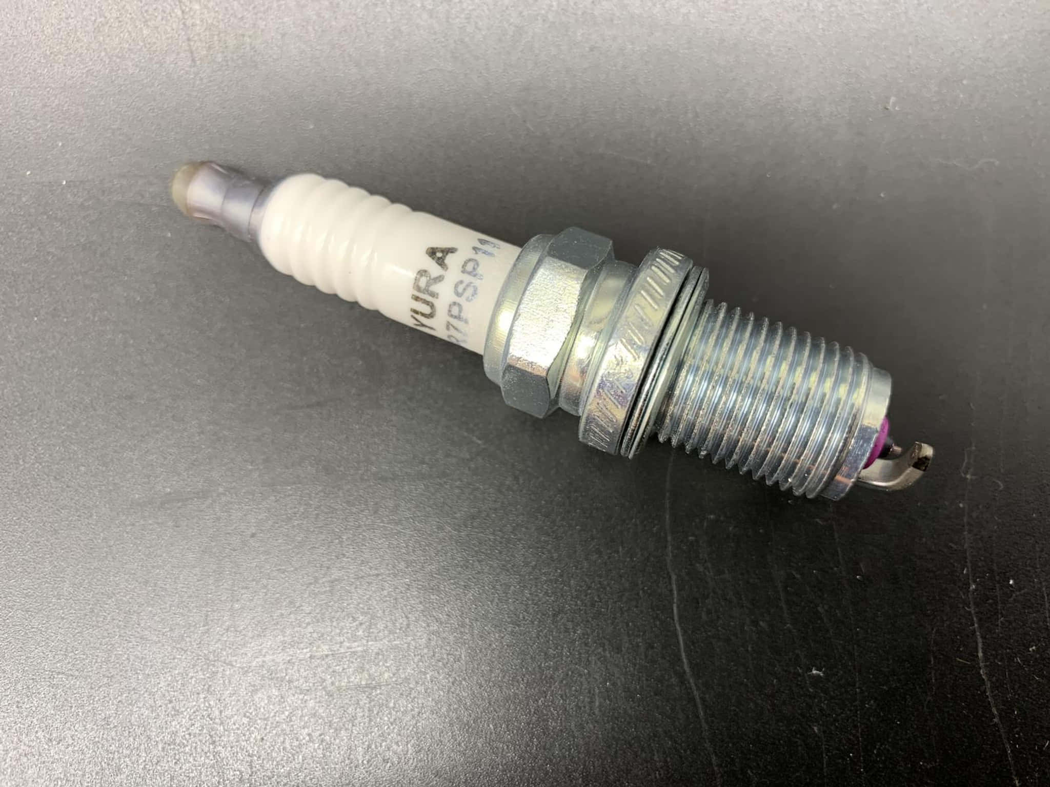 Honda 桌布 壁紙 — 一個銀白色銥金火星塞的特寫，放置在深色紋理表面上。