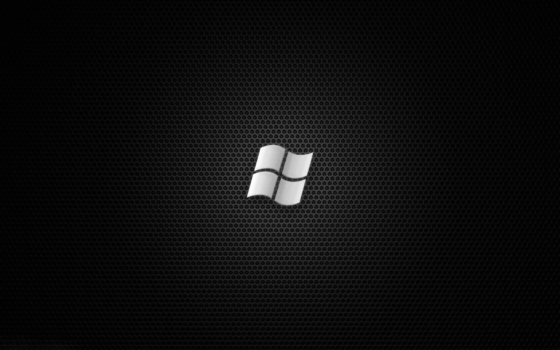 Black Desktop 桌布 壁紙 — 一個銀色Windows標誌居中於黑色穿孔金屬紋理背景上。