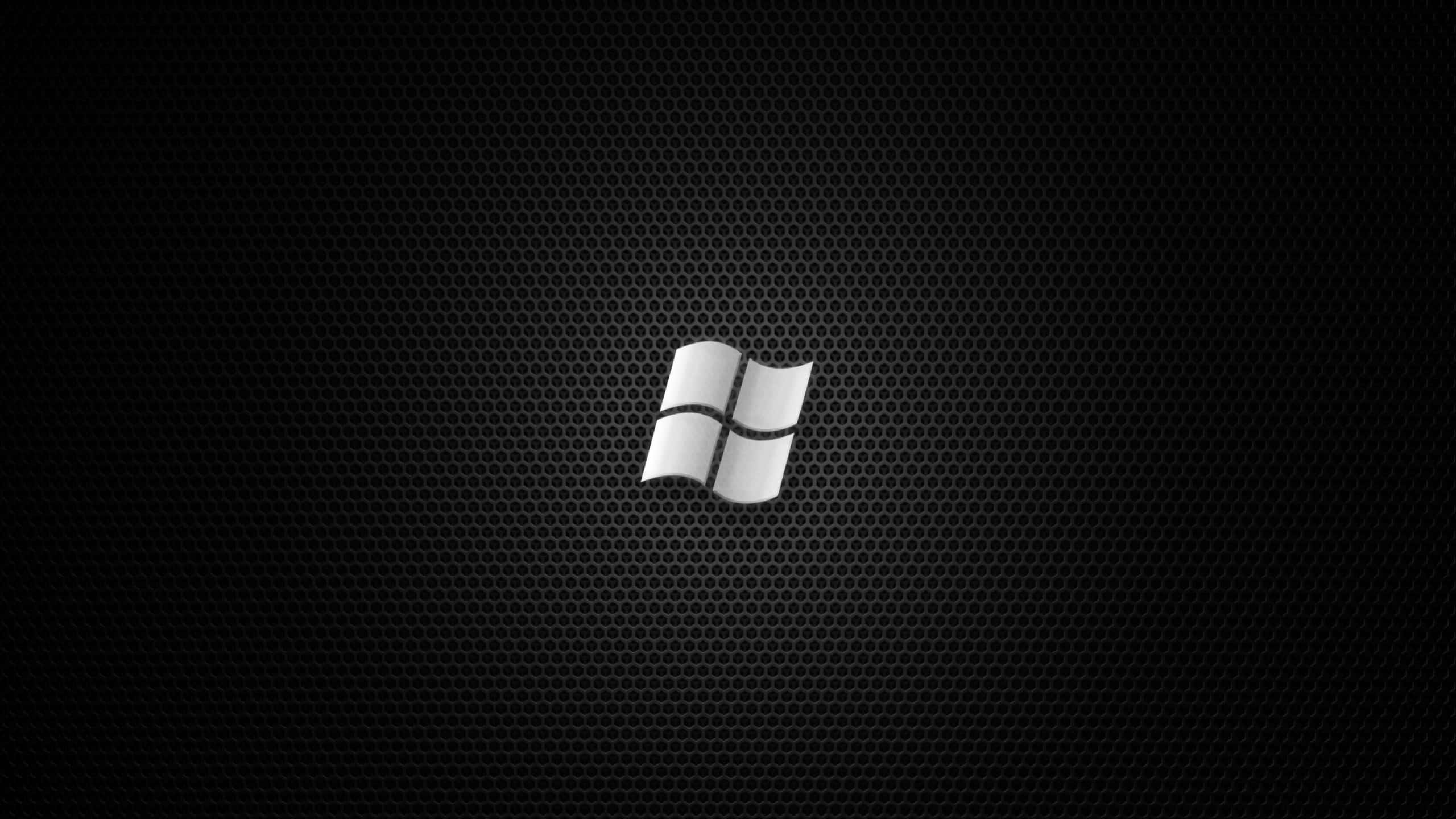 2560x1440 Black 桌布 壁紙 — 一個銀色Windows標誌居中於黑色穿孔金屬紋理背景上。