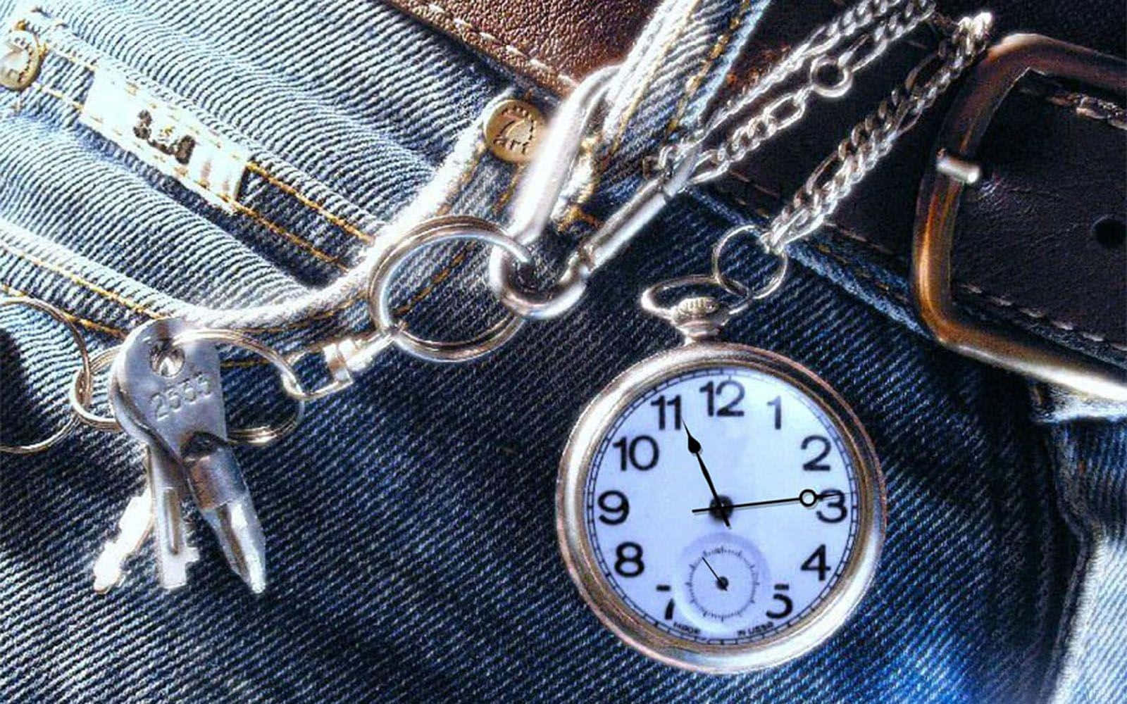 Jeans 桌布 壁紙 — 一個銀色懷錶和鑰匙放在藍色牛仔褲上，附近有一個皮革皮帶扣。