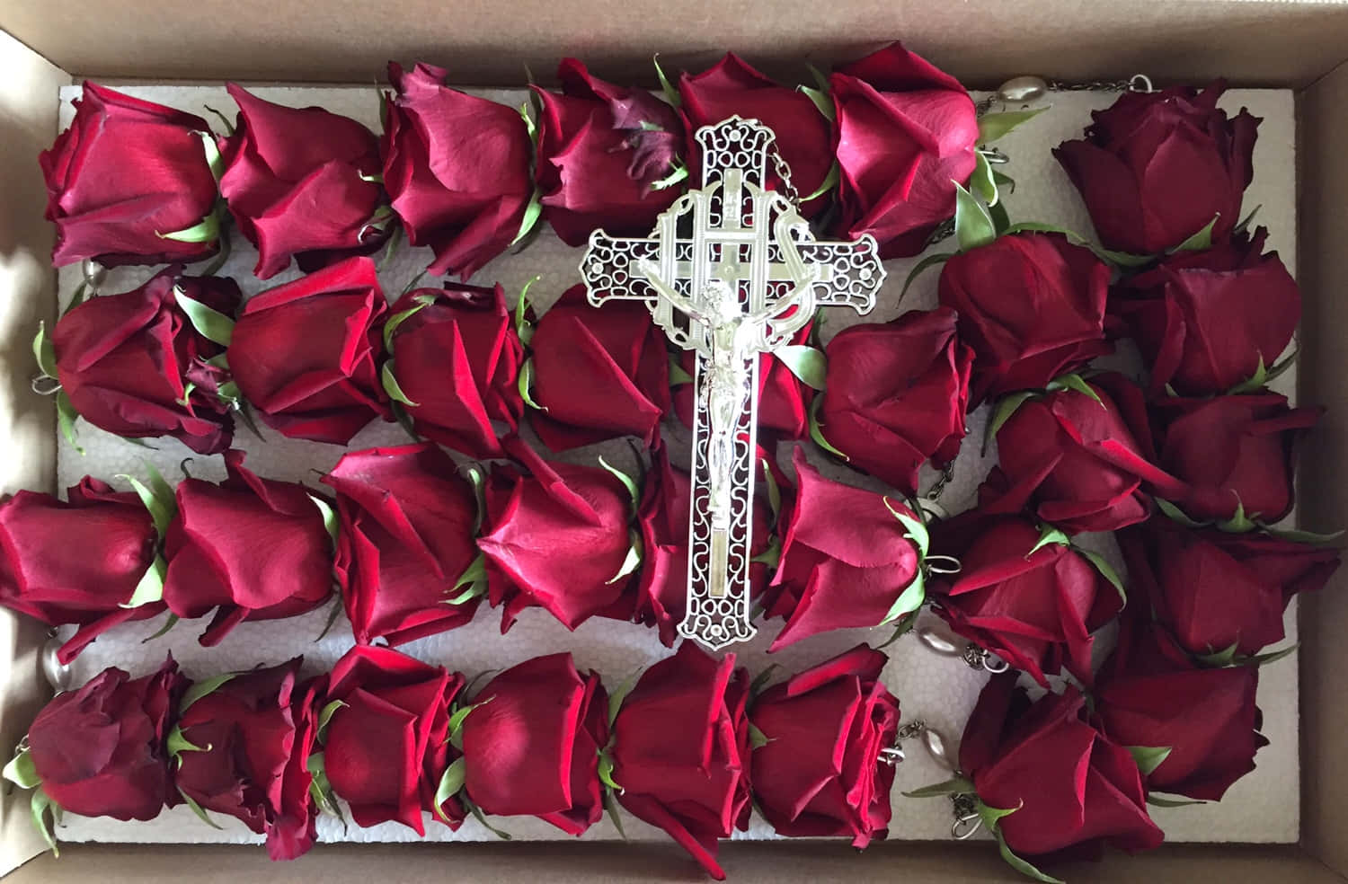 Roses 桌布 壁紙 — 一個銀色華麗十字架安放在一床深紅玫瑰上，玫瑰排列在紙板箱中。