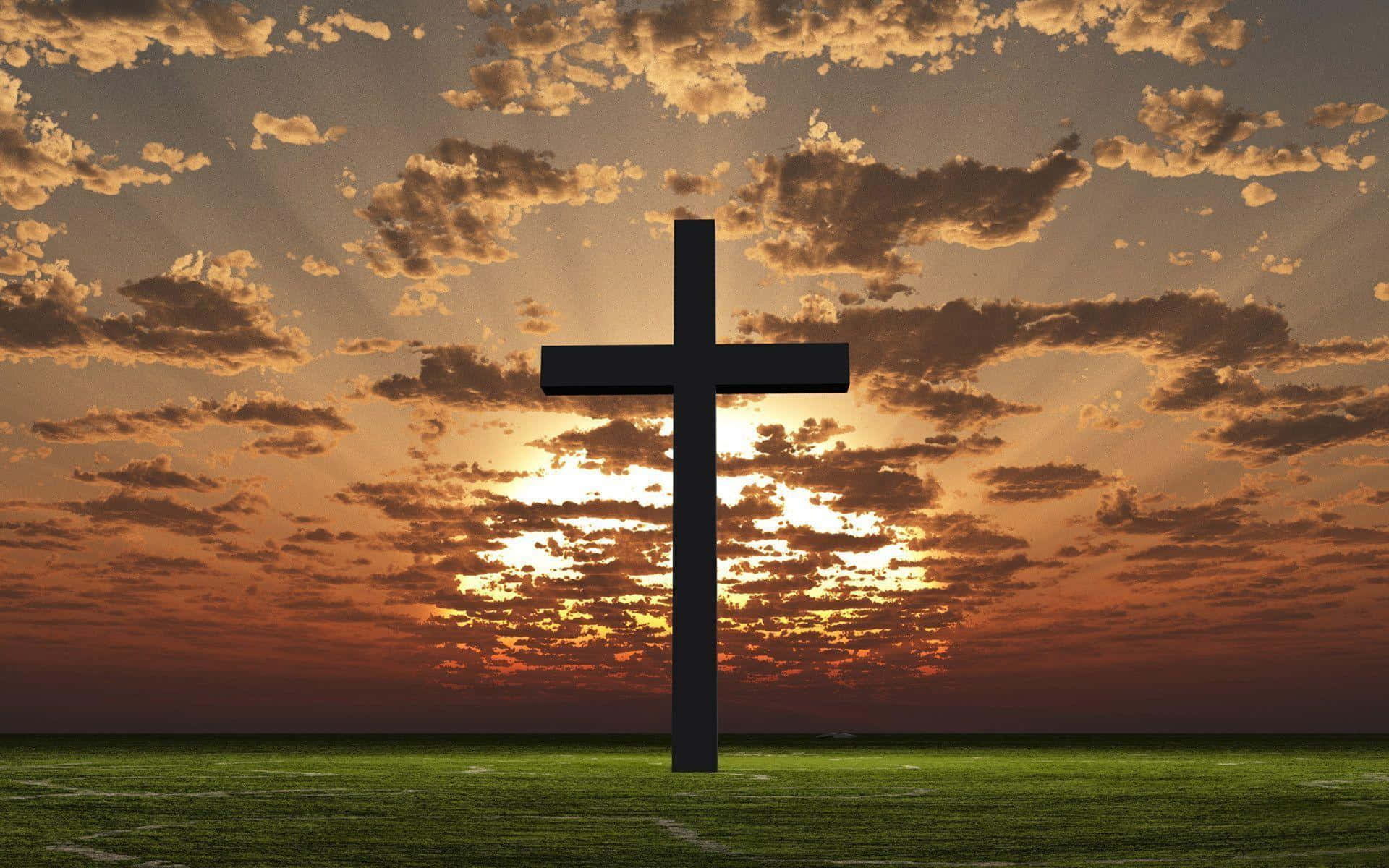 Cool Cross 桌布 壁紙 — 一個銳利的黑色十字架獨自矗立在草地上，背景是帶有金色雲彩的戲劇性日落天空。