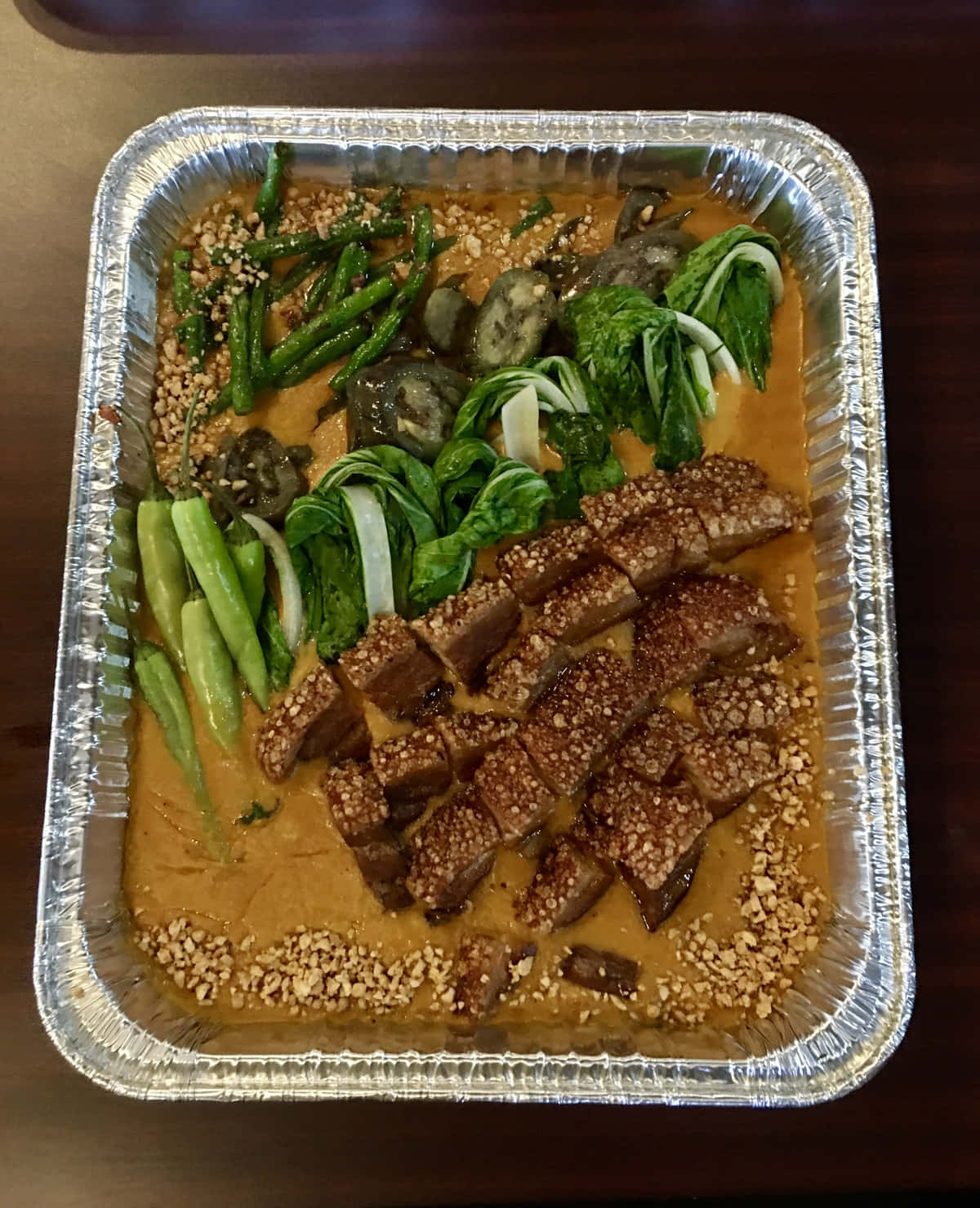 meat 桌布 壁紙 — 一個錫紙托盤盛載著豐富的花生醬菜餚，配以脆皮五花腩、四季豆和白菜，並撒上芝麻作裝飾。