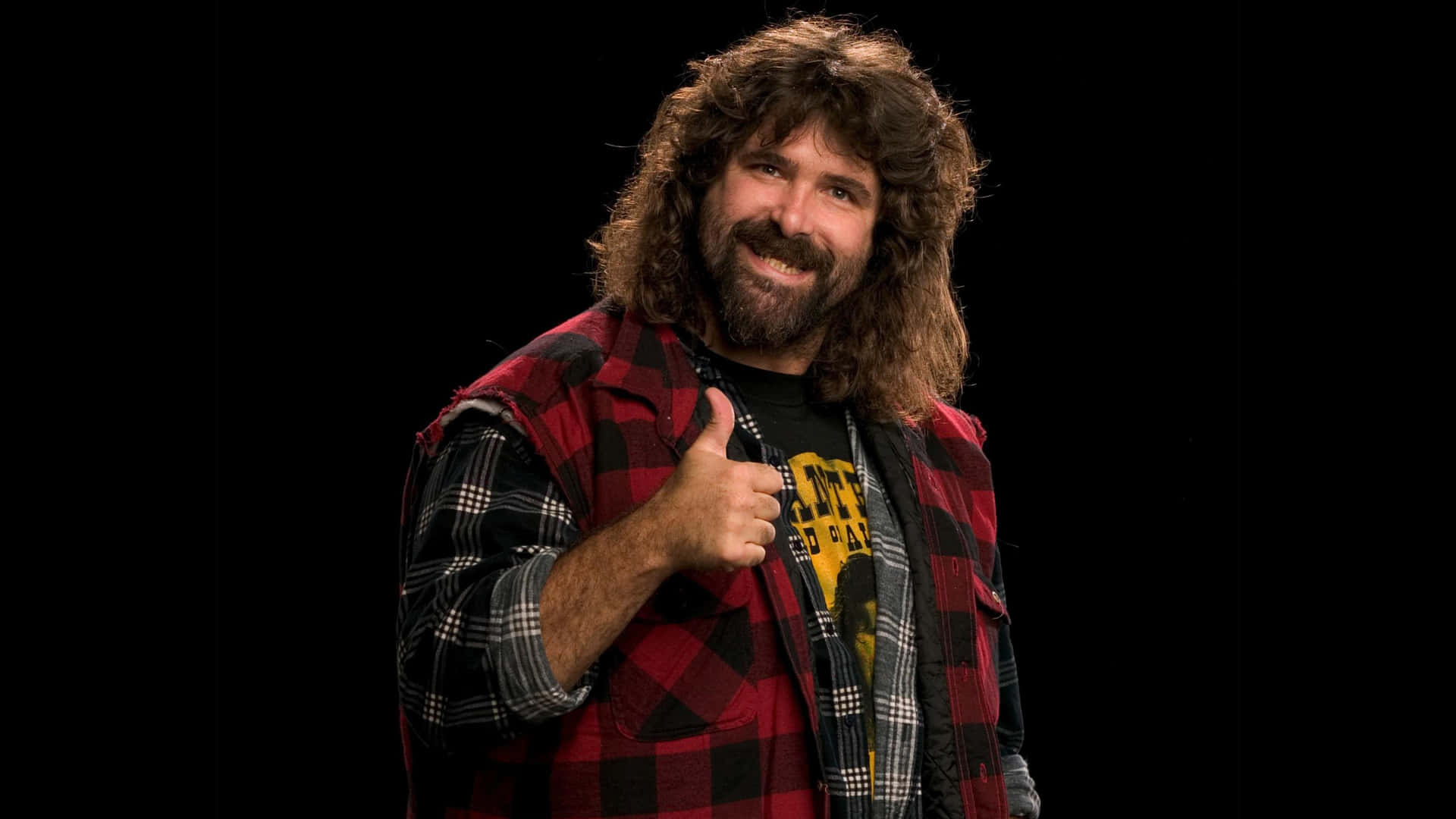 WWE 桌布 壁紙 — 一個長捲髮和鬍鬚的男人，穿著紅色格子襯衫，在黑色背景前豎起大拇指。