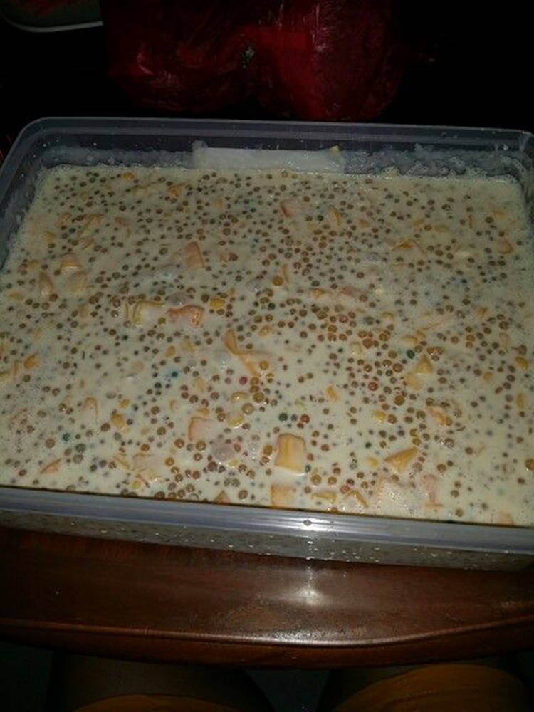 甜點 桌布 壁紙 — 一個長方形塑膠容器盛裝著奶油狀甜點，上面放有色彩繽紛的珍珠和切塊水果，燈光昏暗。