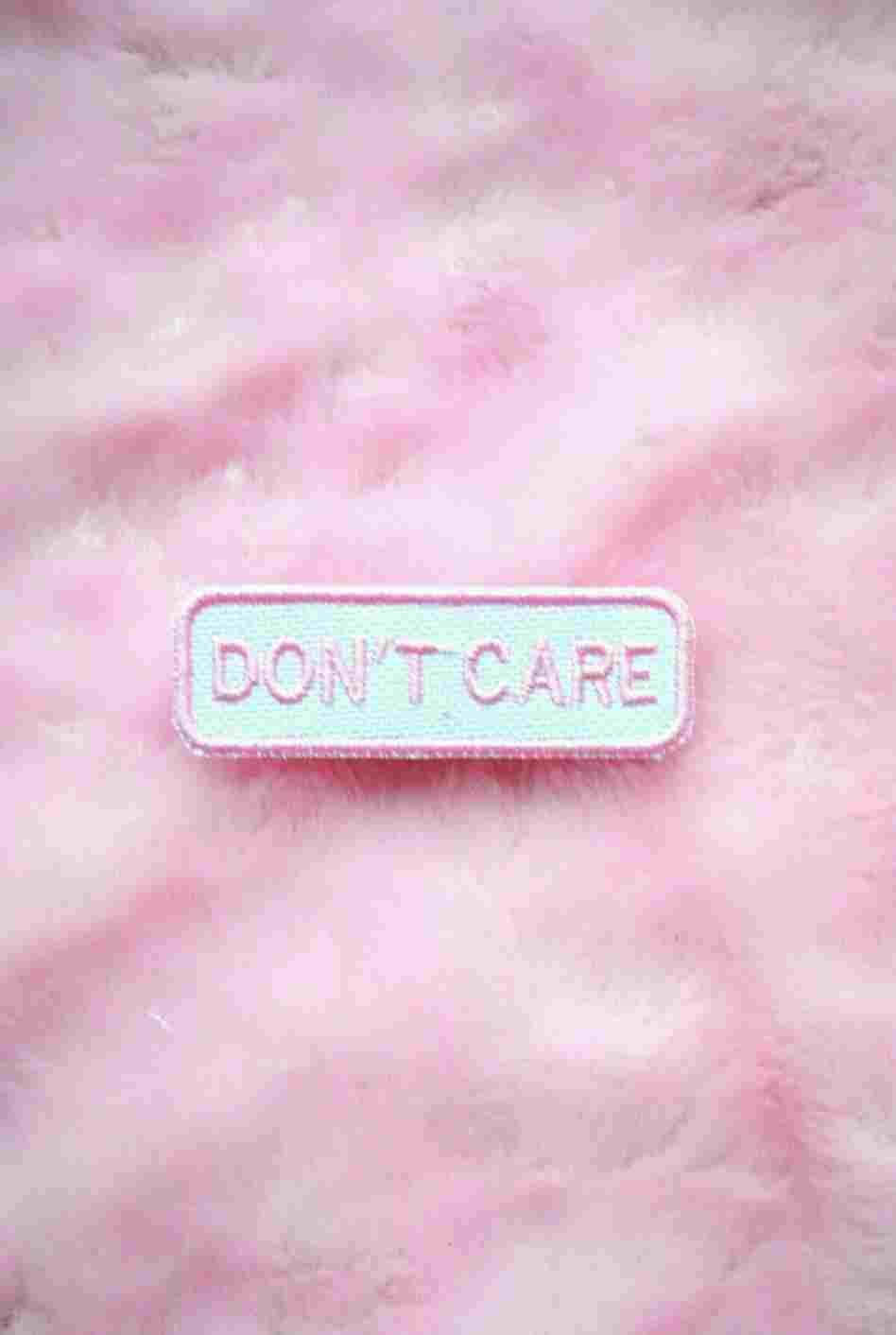 Pink Aesthetic Tumblr 桌布 壁紙 — 一個長方形的刺繡補丁，上面寫著「DON'T CARE」，放在一個柔軟的粉紅色毛茸茸表面上。