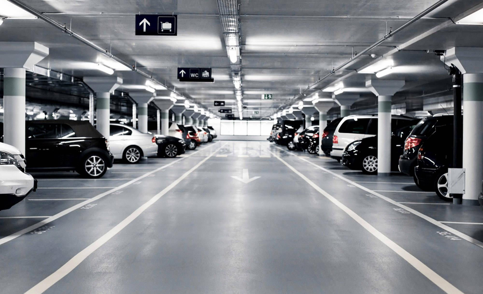 汽車 桌布 壁紙 — 一個長而空的停車場，在明亮的螢光燈下停著一排排汽車。