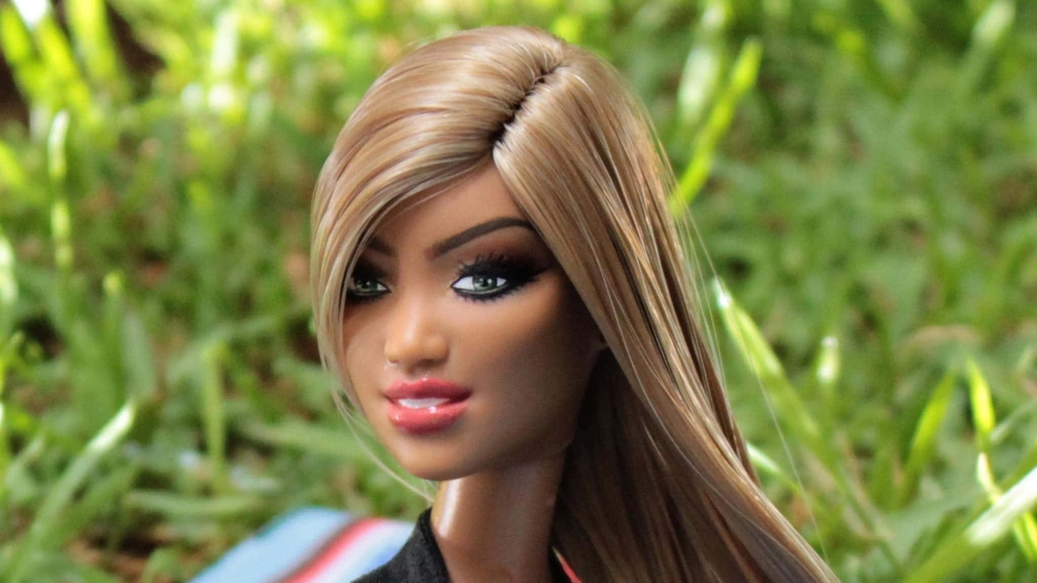 Barbie Doll 桌布 壁紙 — 一個長金髮綠眼娃娃的特寫，背景是模糊的綠色草地。