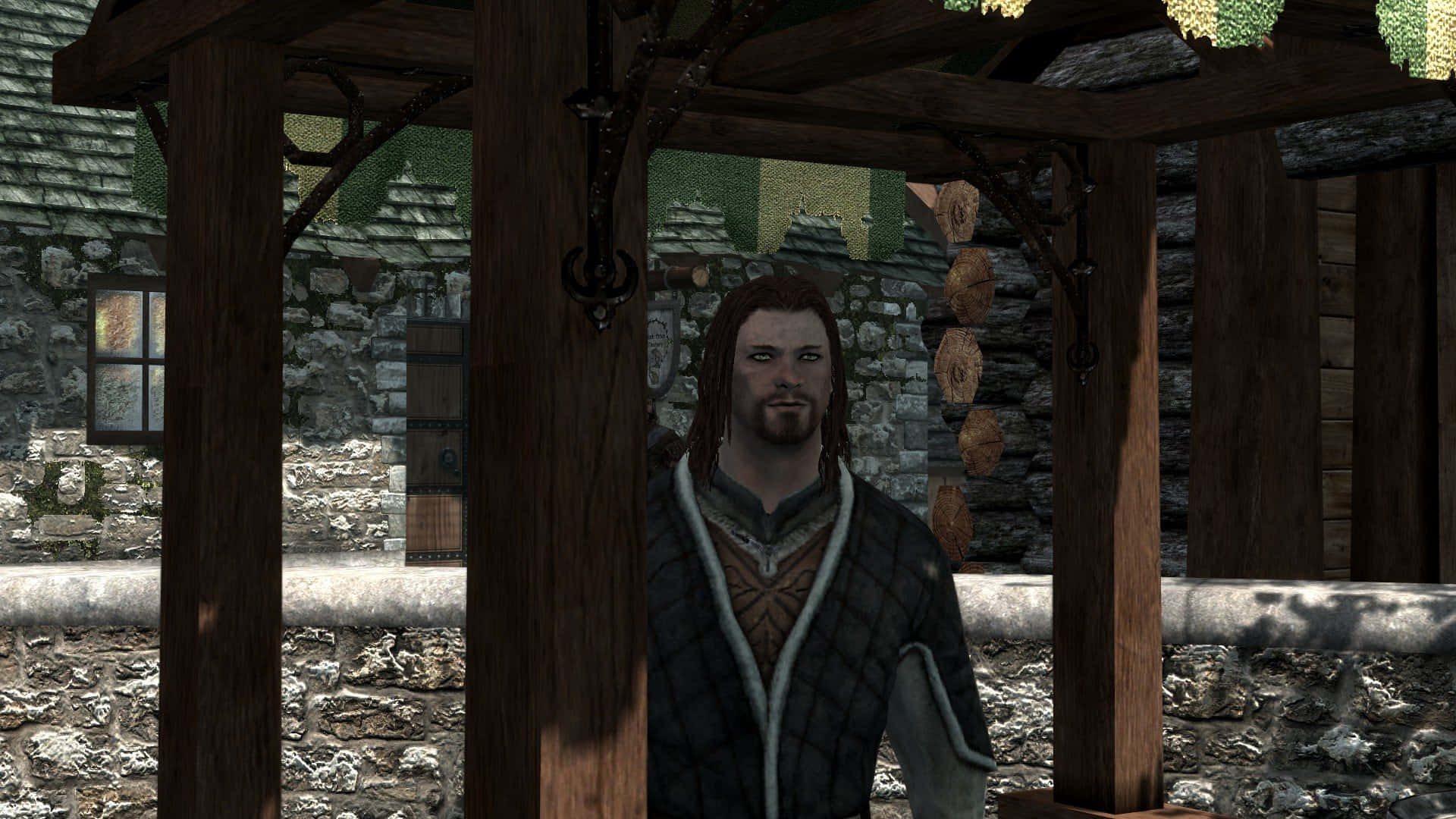 Skyrim Brynjolf 桌布 壁紙 — 一個長髮男人站在一個掛著燈籠的質樸石村的木製涼亭下。