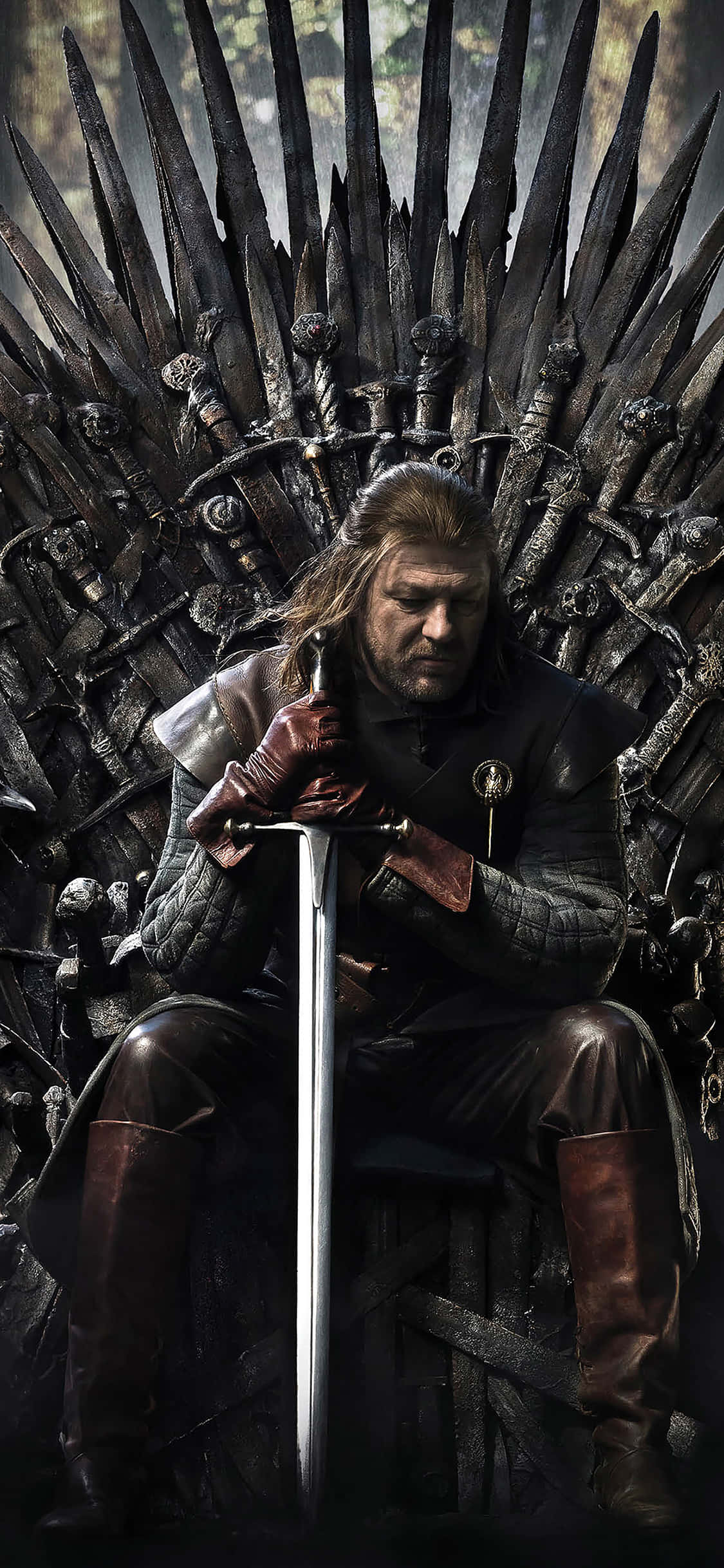 Game Of Thrones iPhone 桌布 壁紙 — 一個長髮男子在昏暗的森林環境中莊嚴地坐在鐵王座上，手持一把劍。