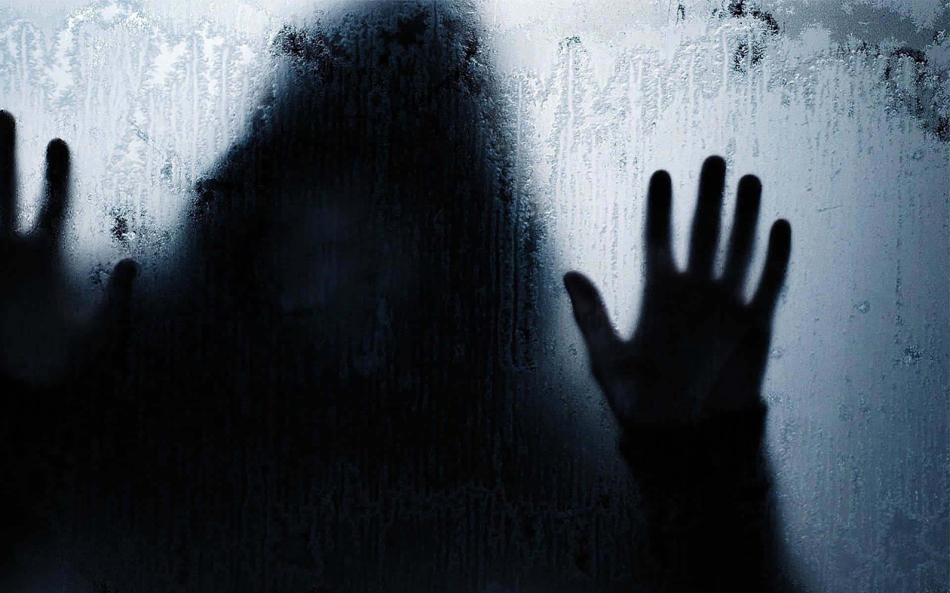 Spooky Halloween 桌布 壁紙 — 一個長髮的陰影人物將手按在結霜的窗戶上，營造出寒冷而詭異的場景。