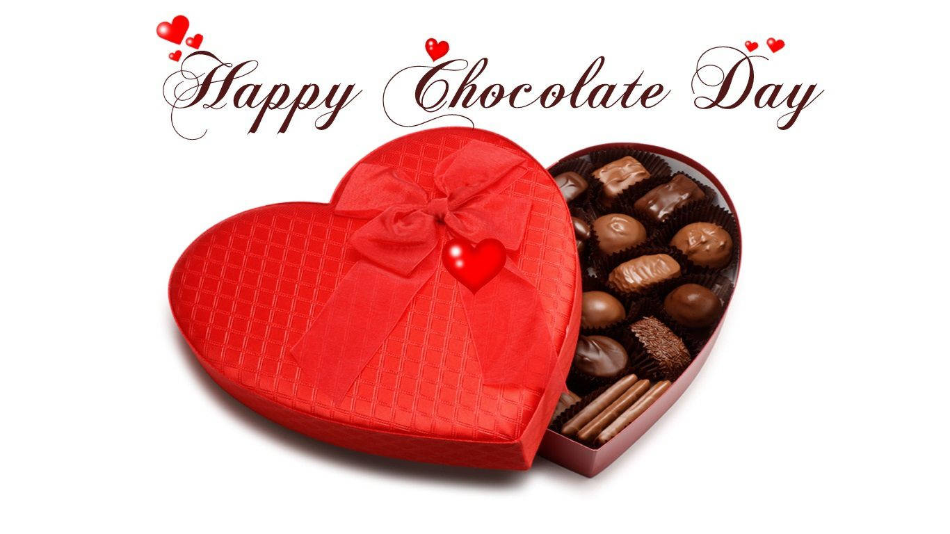Chocolate Day 桌布 壁紙 — 一個閃亮的紅色心形巧克力盒，飾有蝴蝶結和小心形，打開後露出各種巧克力，背景為白色。