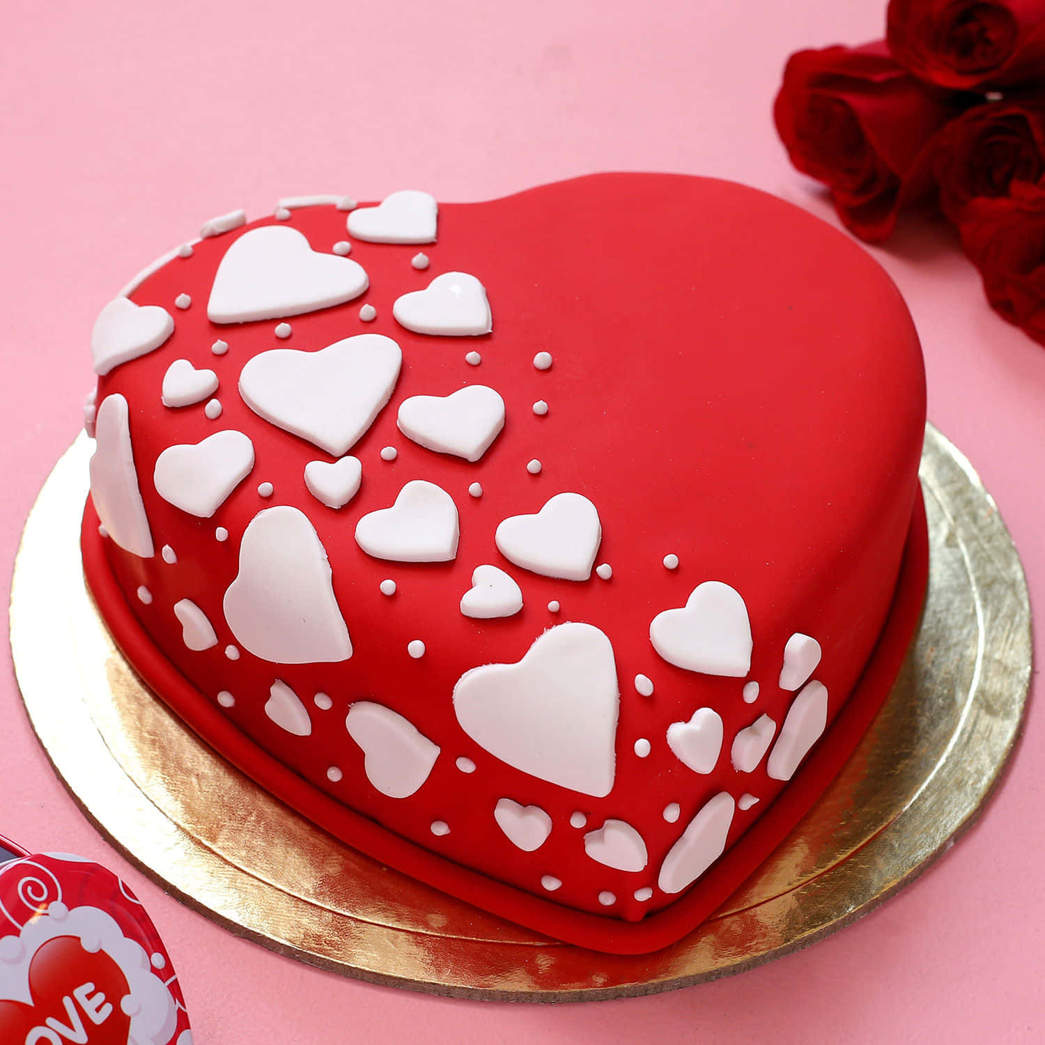 Cake Fondant 桌布 壁紙 — 一個閃亮的紅色心形蛋糕，上面裝飾著白色翻糖心形和圓點，放在金色盤子上，旁邊有紅玫瑰。