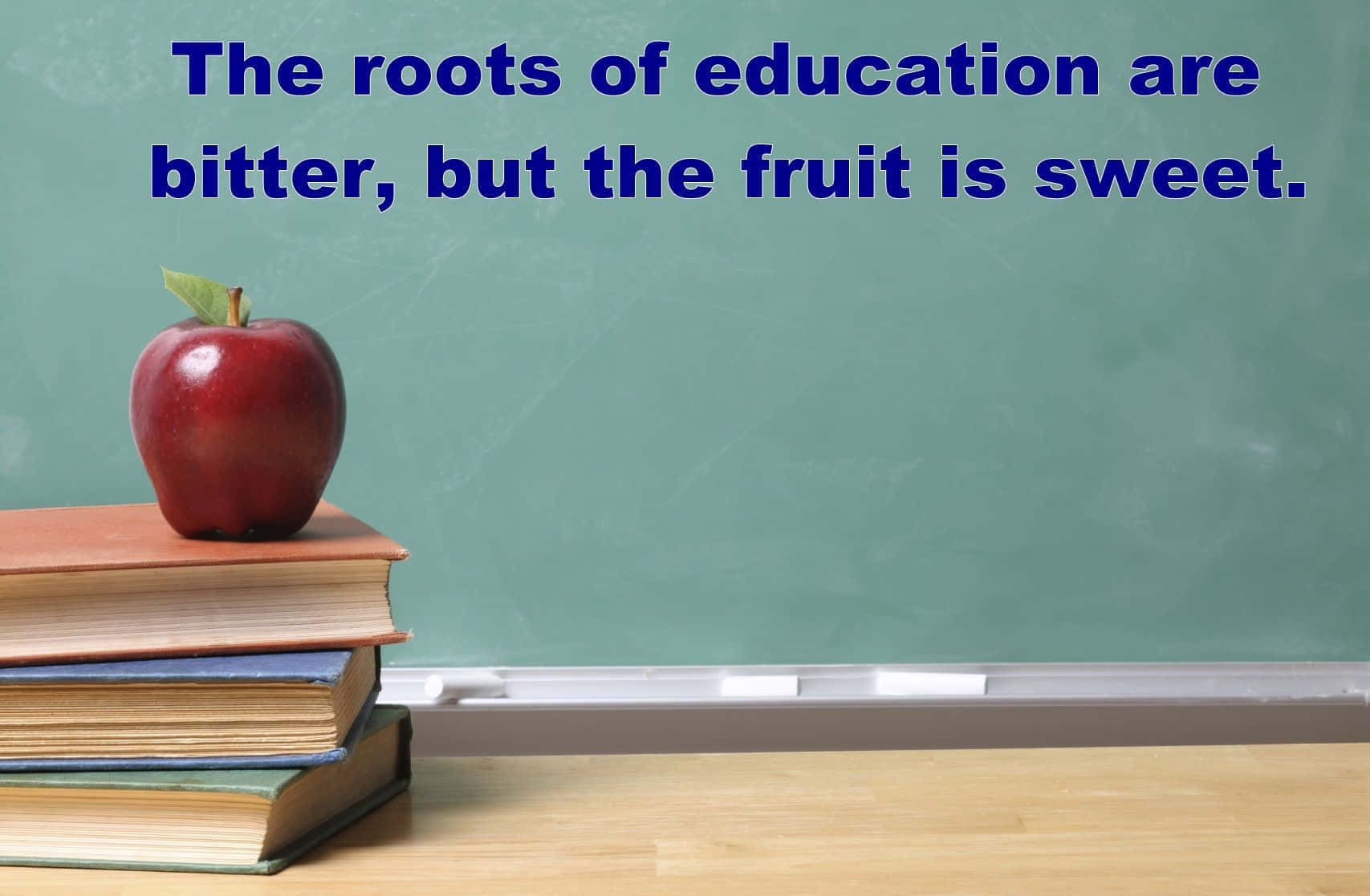 Educated 桌布 壁紙 — 一個閃亮的紅蘋果放在木桌上的一堆書上，前面是一塊帶有教育格言的綠色黑板。